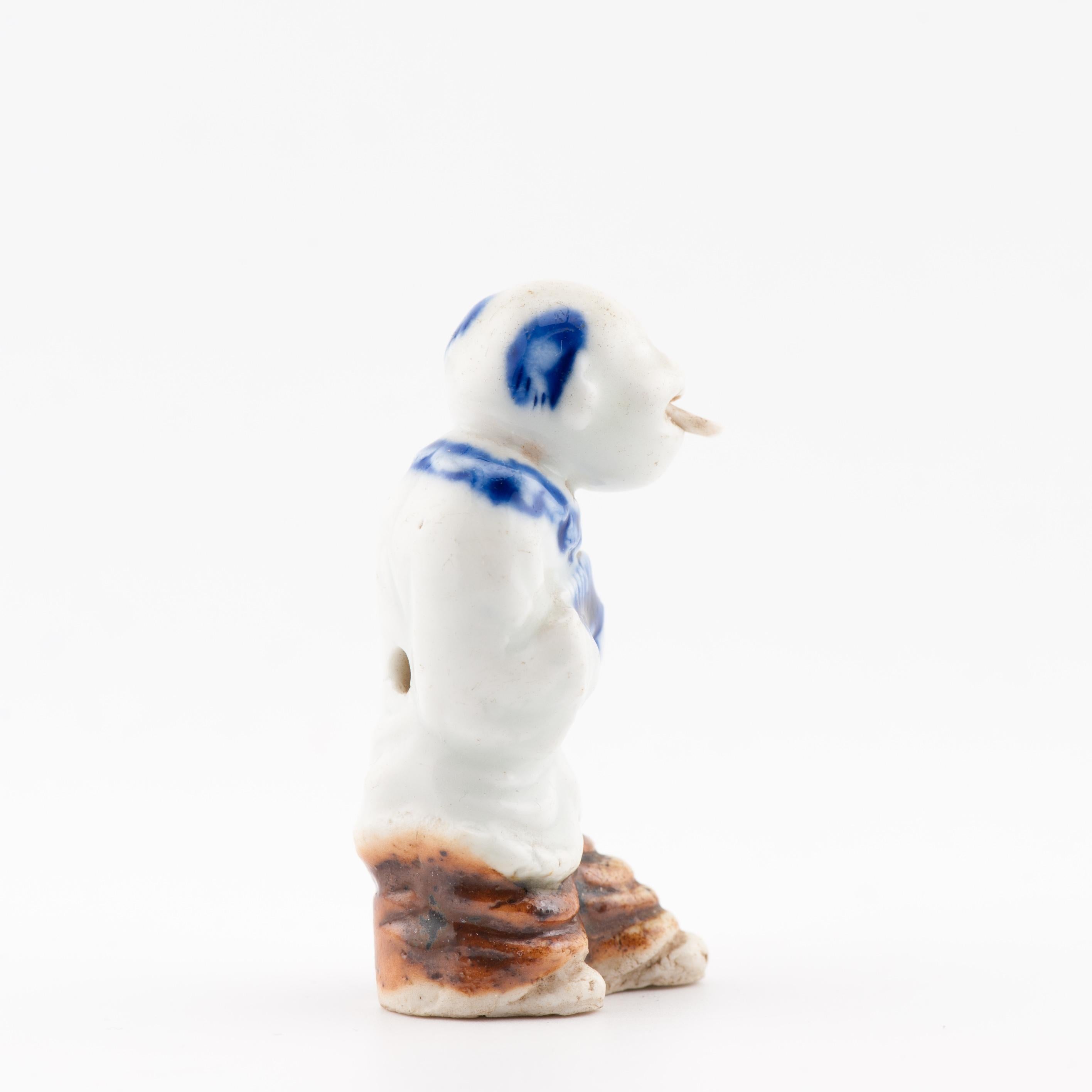 Il s'agit d'un netsuke ancien en porcelaine de Hirado d'une facture très inhabituelle, représentant un singe espiègle habillé en danseur de Sanbosa. La figure est modelée avec netteté, avec une glaçure bleu cobalt et brun fer appliquée sur la coiffe