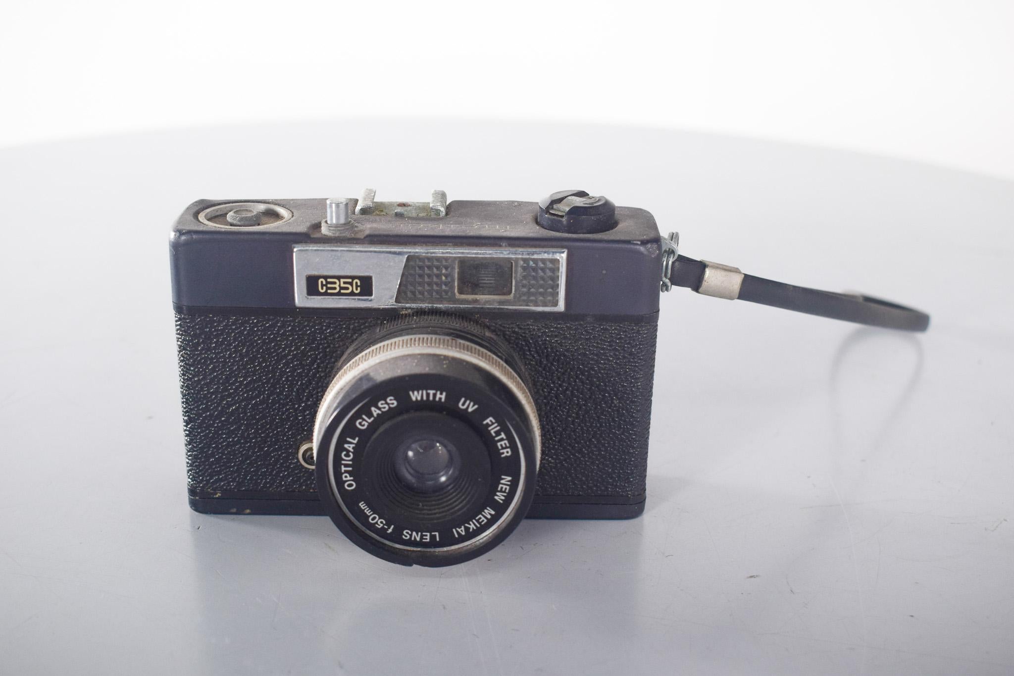 Appareil photo Meikai.  Équipé d'un nouvel objectif Meikai f-50mm. Cet objectif simple, doté d'un verre optique et d'un filtre UV intégré, suggère un équipement destiné aux amateurs ou aux passionnés de photographie occasionnels. Avec son corps en