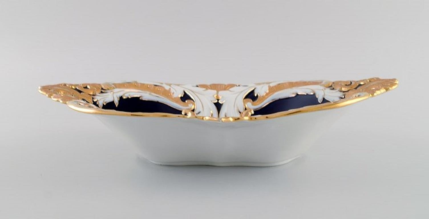 Antique Meissen bowl in hand-painted porcelain. 
Foliage in white and gold on a dark blue background. Early 20th century.
Measures: 31 x 19,5 x 6,5 cm.
In excellent condition.
3rd factory quality.
Stamped.