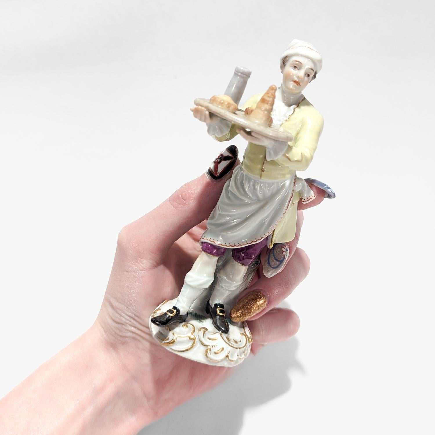 A fine Meissen porcelain figurine of a Baker or Pastry Vendor.

From the Cris of Paris series.

Model no. 1.

Designed by Peter Reinicke ca. 1755

The figurine depicts a man wearing baker's garb overtop his yellow & purple clothes holding a tray