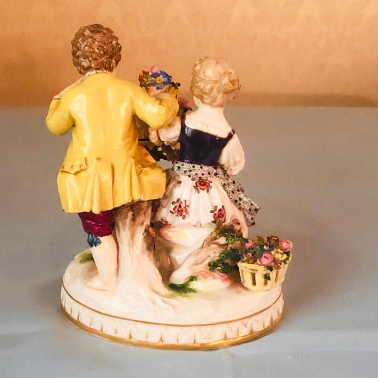 Meissen figural group of girl and boy with two birds out of their cage. They have a flower garland and flowers in their openwork basket with one bird near their feet and the other bird on top of the cage. It is from 1880s-1890s. It is a very