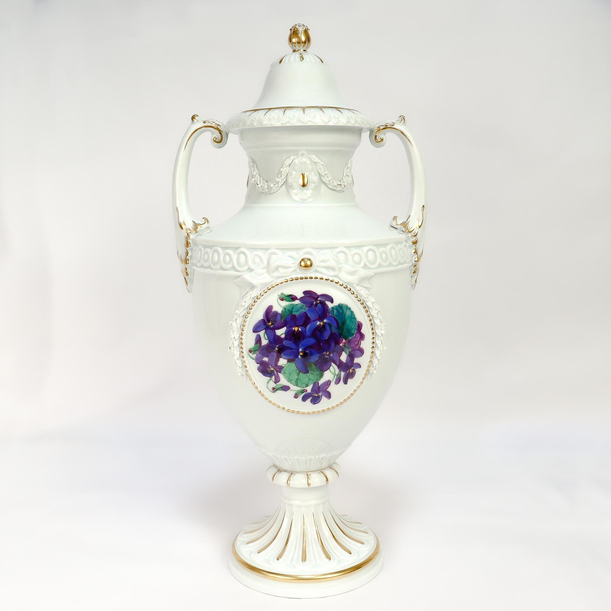 Eine feine signierte deutsche Porzellan-Deckelurne oder große Vase.

Von Meissen.

Verziert mit applizierten und erhabenen Bändern, Lorbeeren und geometrischen Mustern.

Die Seiten sind mit Stiefmütterchen- und Veilchenblüten bemalt (sehr