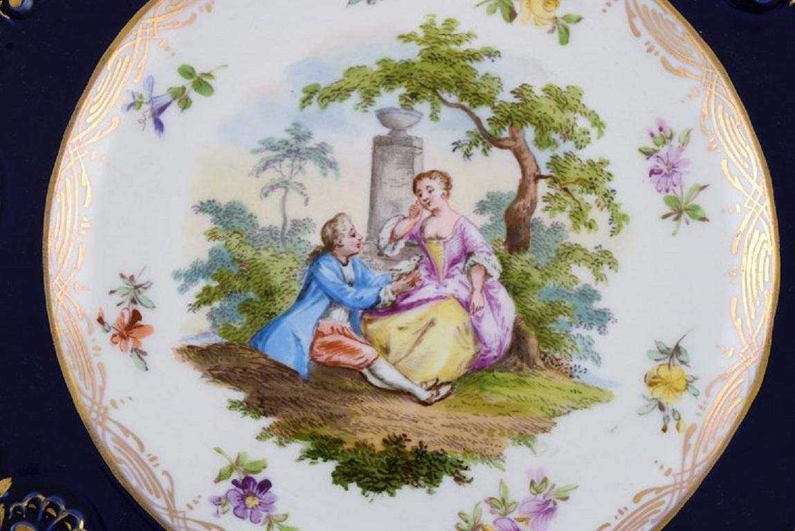 Assiette ancienne de Meissen en porcelaine peinte à la main. Scène romantique, bordure bleue avec décorations dorées. 
Fin du 19e siècle.
Diamètre : 22 cm.
En parfait état.
Estampillé.
1ère qualité d'usine.
