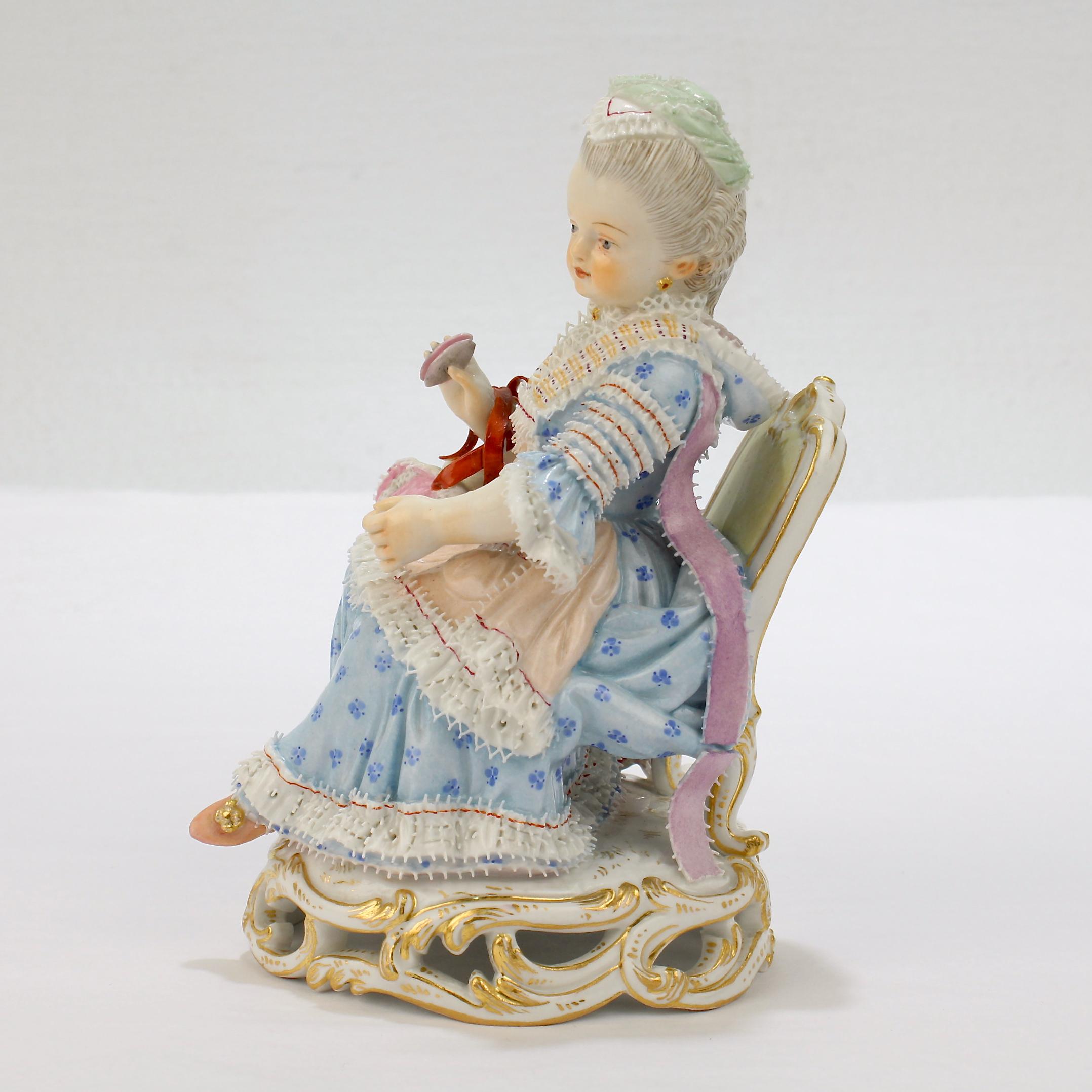 A fine antique Meissen porcelain figurine of a seated girl.

Depicting a young girl seated in a chair with a bonnet wrapped around one arm and holding a thread winder in the same hand. Her dress and headdress are both finished with lace.

Model