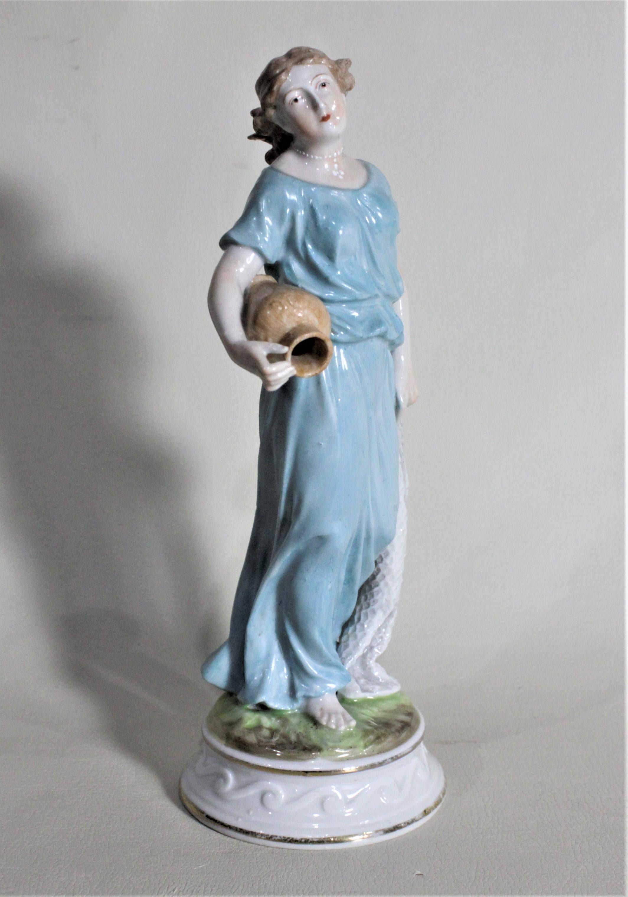 This well executed porcelain figurine was made by the Meissen factory of Germany in circa 1900. This figurine depicts a woman in a long flowing blue dress carrying a terracotta water pot. The piece is clearly marked with the cobalt blue crossed
