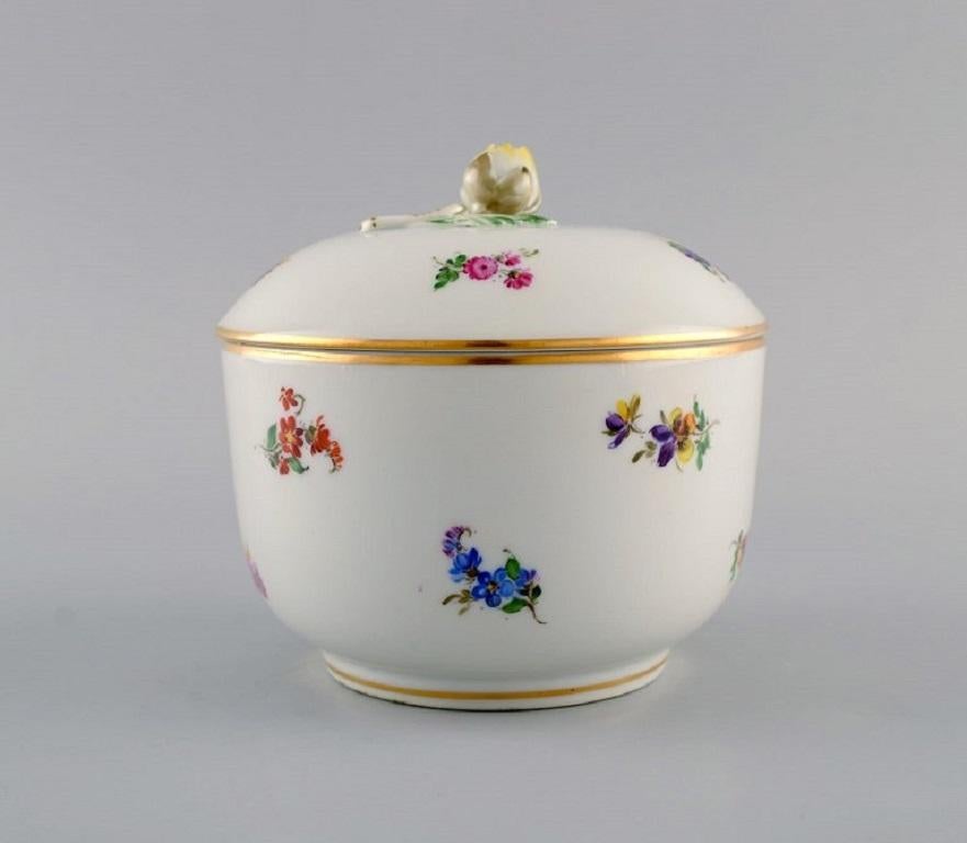 Antique bol à couvercle en porcelaine de Meissen avec fleurs peintes à la main et décoration dorée. 
Bouton du couvercle en forme de fleur. Environ 1900.
Mesures : 12 x 11,5 cm.
En parfait état. La fleur sur le couvercle avec petit