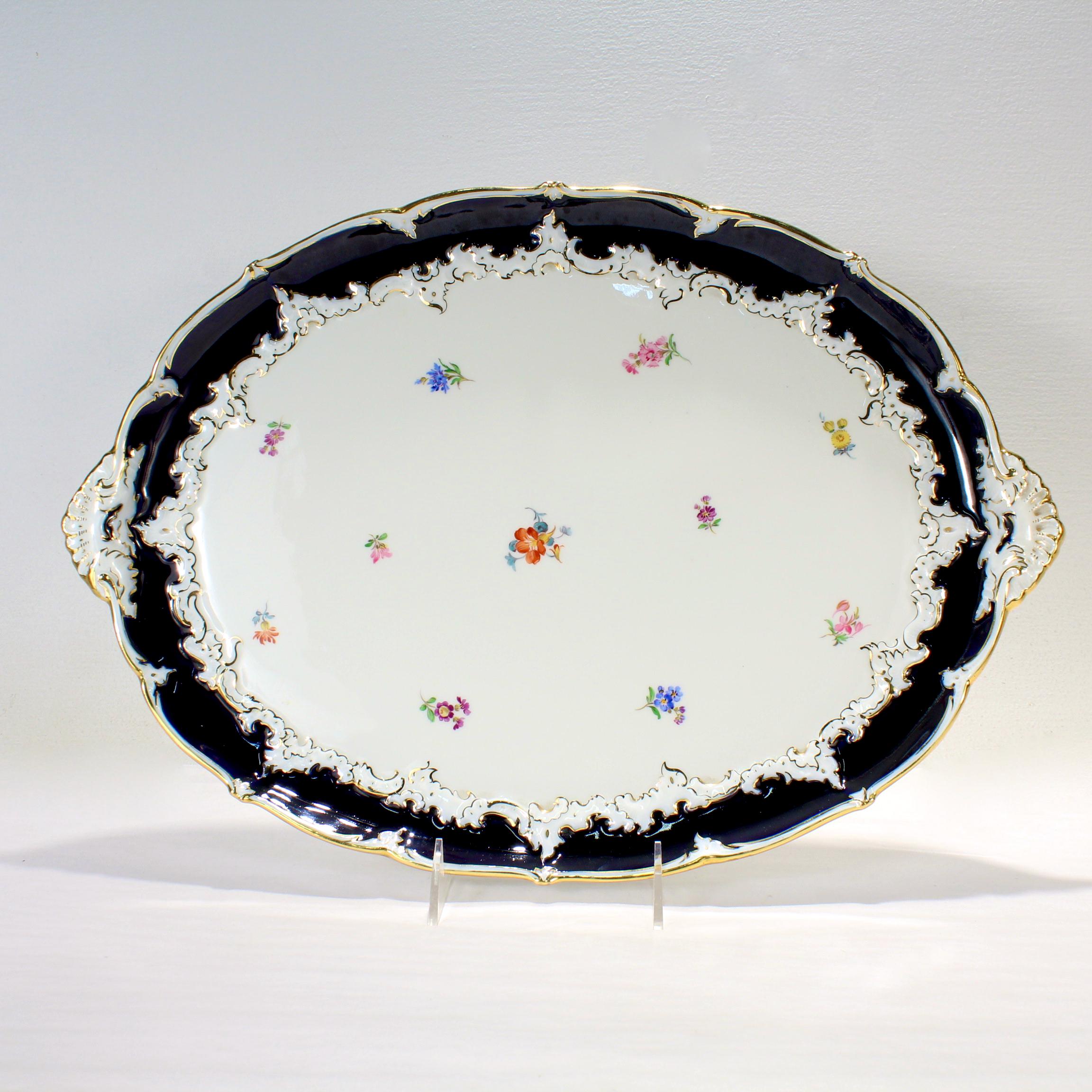 A fine antique porcelain tea tray or serving platter.

By Meissen.

With a scalloped rim and a rich cobalt blue border. 

There are hand painted flowers and gilt highlights throughout.

Simply a wonderful tray from Meissen!

Date:
20th