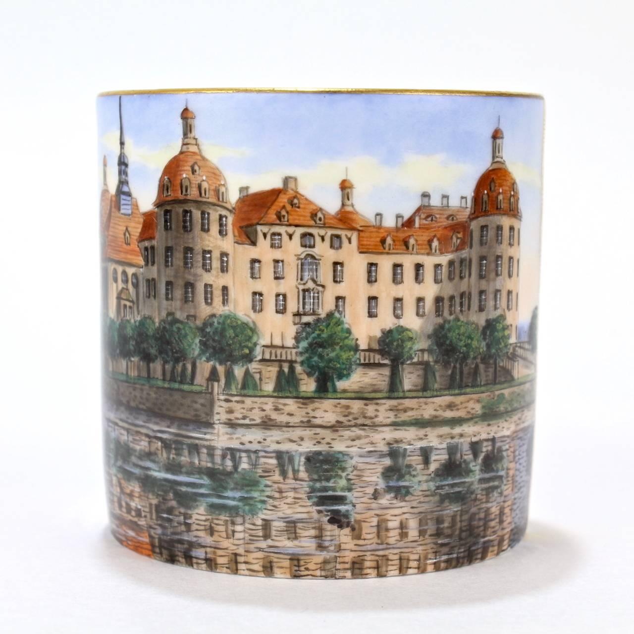 A rare, antique topographical Meissen porcelain coffee cup.

The central finely hand-painted scene depicts the Royal Hunting Lodge at Moritzburg (Königliche Jagdschloss Moritzburg). 

The base bears a blue underglaze crossed swords factory mark,