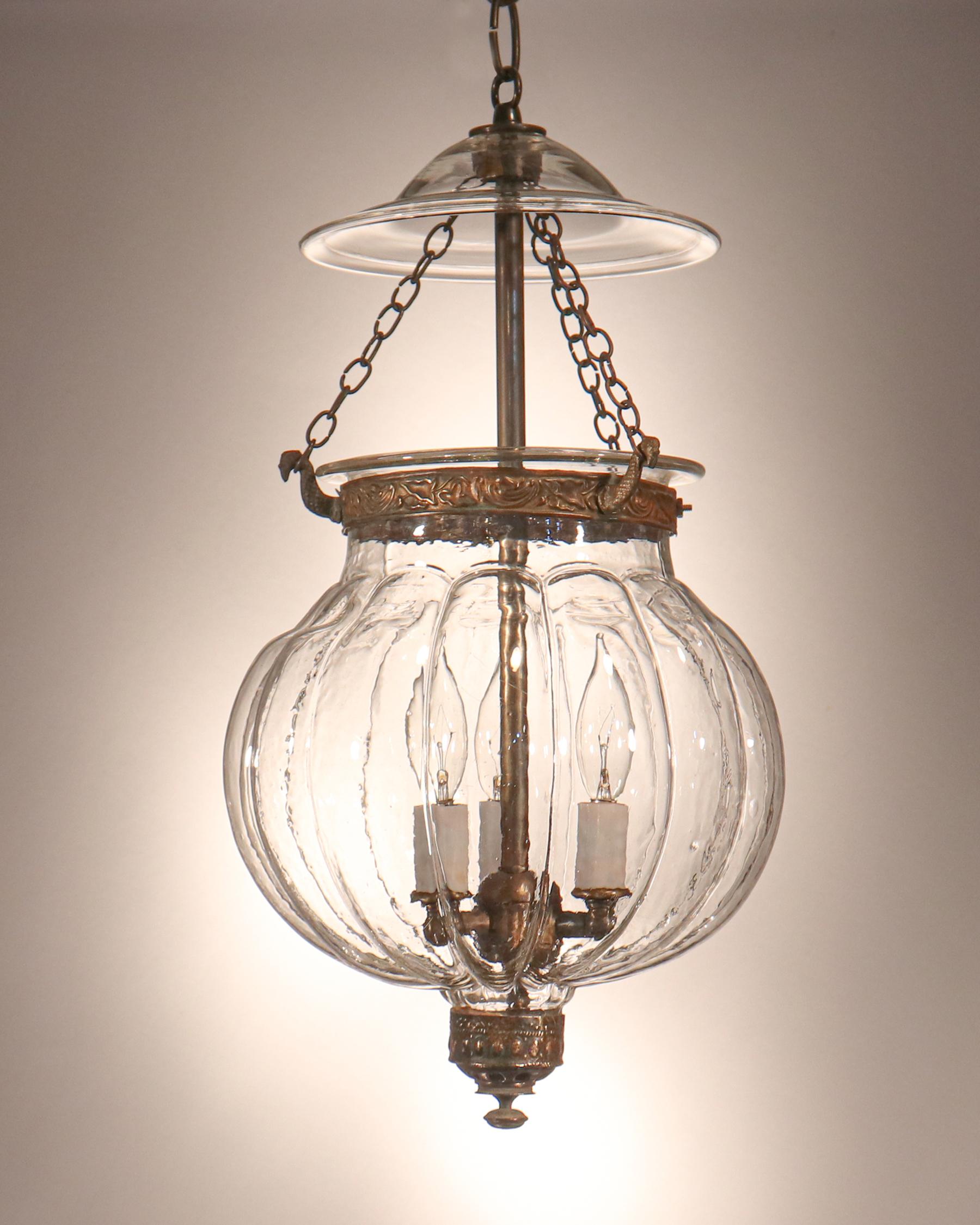 This circa 1870 melon- or pumpkin-shaped bell jar lantern is a rare find. The quality of its hand blown glass is very good, with several desirable air bubbles in the jar and neck. Both the smoke bell and brass finial/candleholder base are original