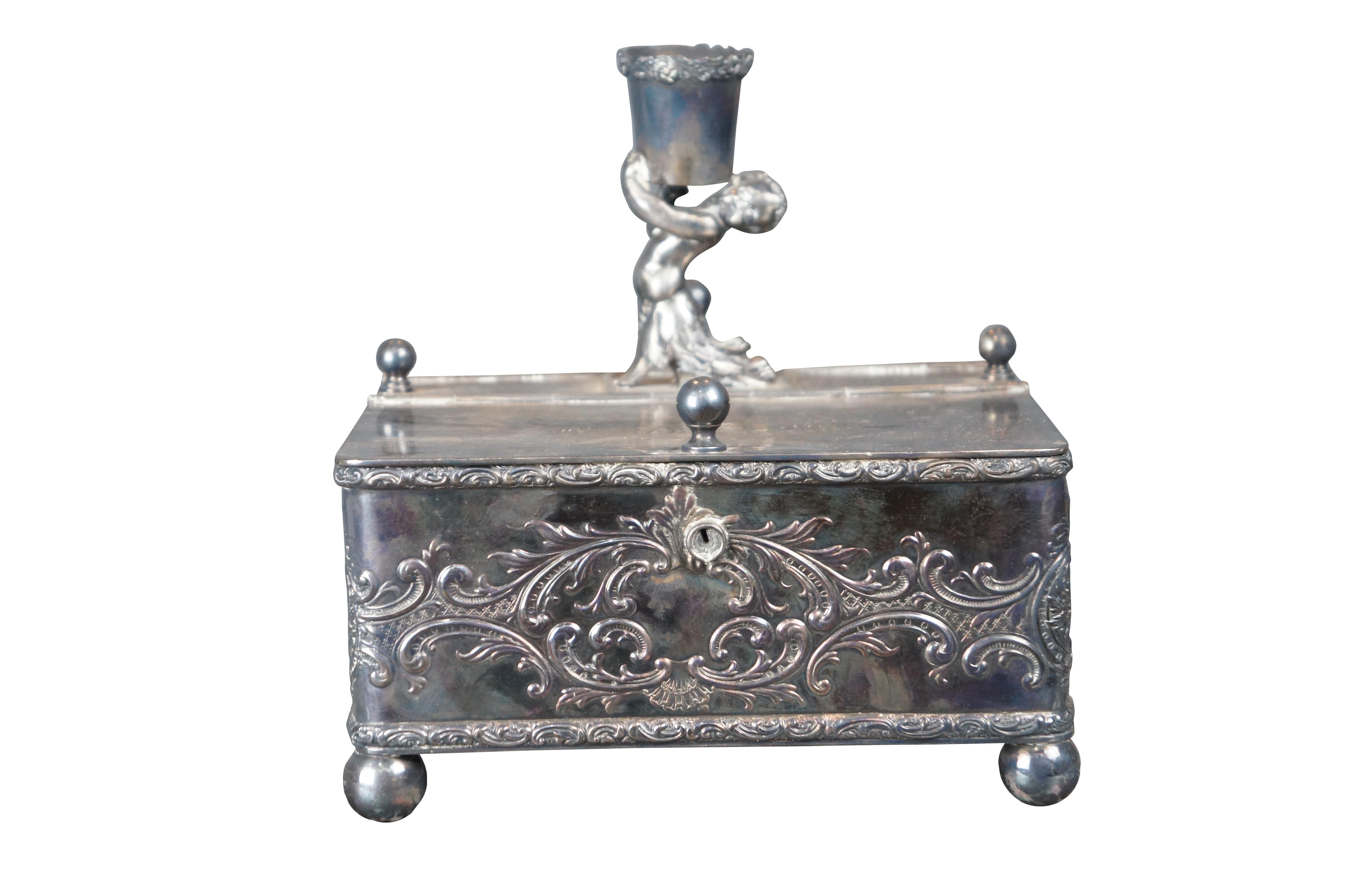 A divided Humidor by Meriden B. Company, Circa 1898. Made from silverplate with chased baroque pattern. The footed box has two large compartments and two small opening that allow access to the center. Along the top is a cherub holding a candleholder