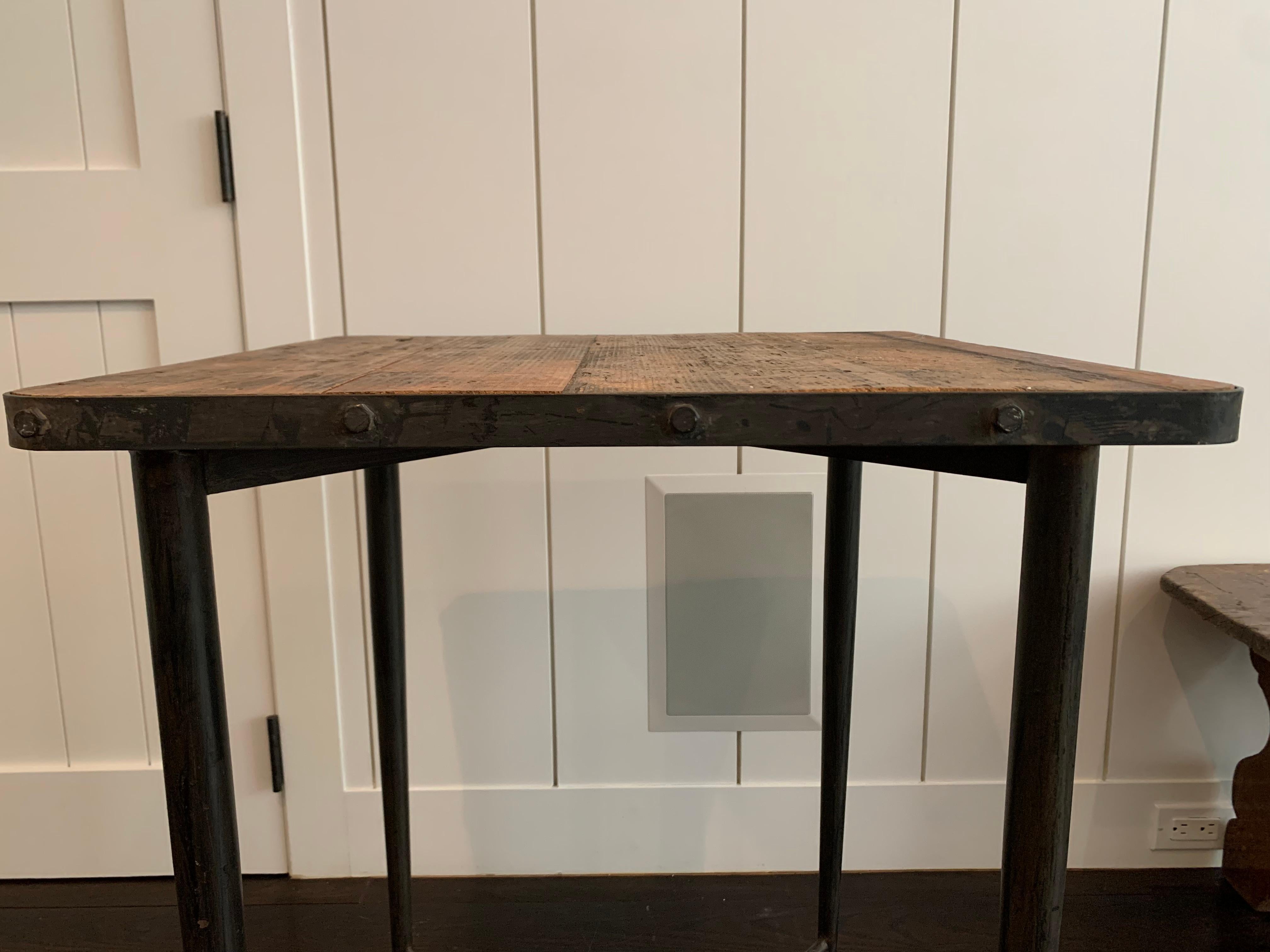 Table ancienne avec plateau en bois vieilli et pieds en métal avec têtes de clous.