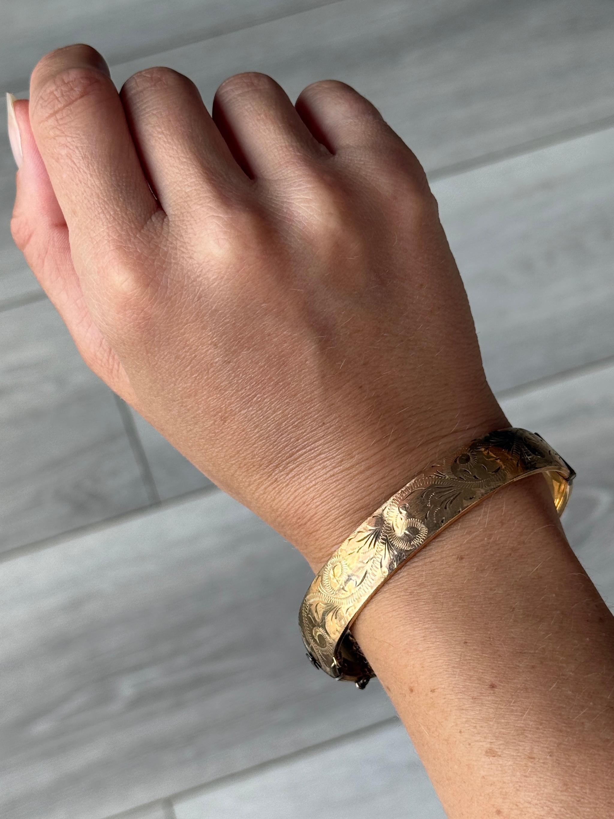 Este precioso brazalete de núcleo metálico tiene un maravilloso grabado y está recubierto de oro de 1/5 de 9 ct. 

Diámetro interior punto más ancho: 6.2 cm
Circunferencia interior:  17.5cm
Ancho del brazalete: 13 mm

Peso: 21 g