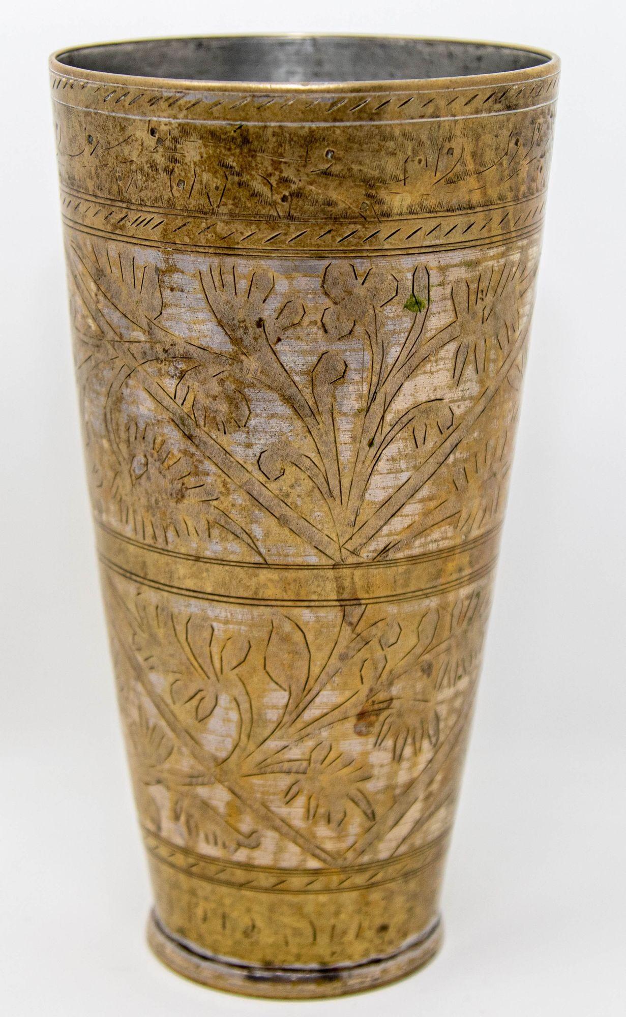 Vaso antiguo de metal plateado martillado y grabado, de estilo mogol, bellamente cincelado a mano y decorado con motivos geométricos y botánicos.
Taza de metal para beber lassi de estilo mogol islámico, única en su género, procedente de la India y