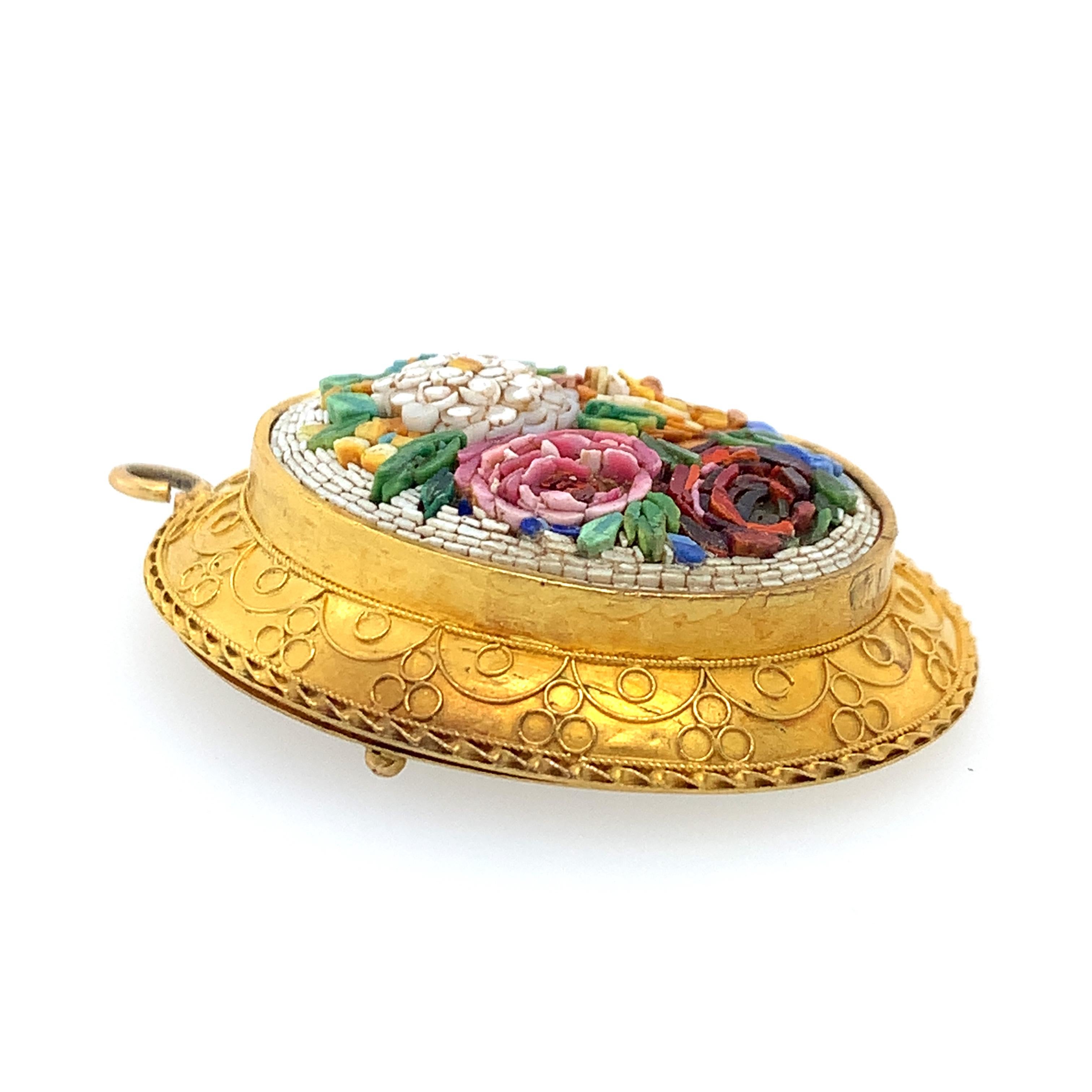 An impressive Victorian 18K gold locket features a Roman micromosaic depicting a floral bouquet. 
This unique artistic tradition was born in Italy in the 18th Century, flourished in the 19th Century, and remains very much alive today. Influenced by