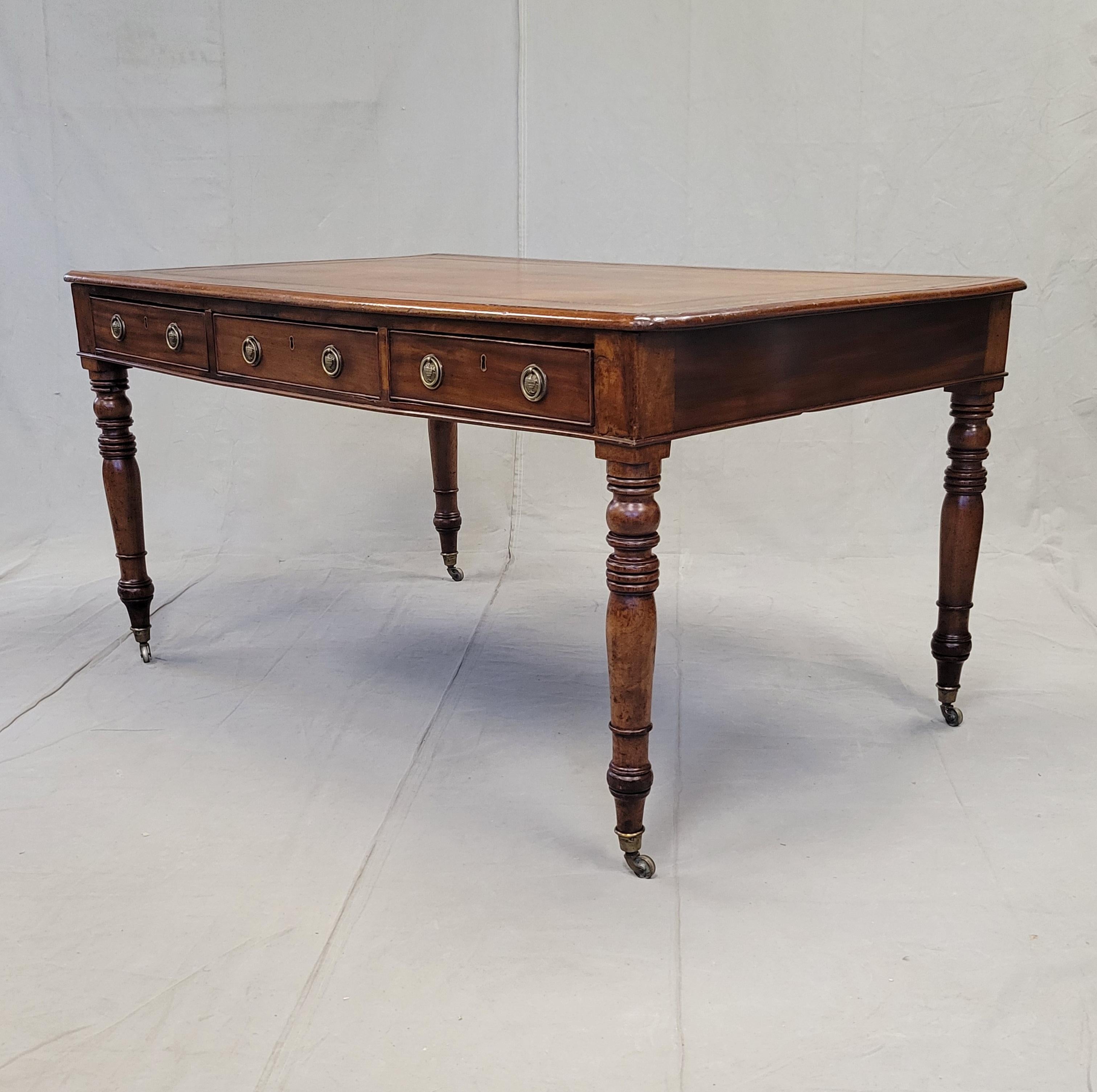 Splendido scrittoio antico in mogano inglese della metà dell'800 con piano in pelle marrone con motivi di conchiglie e foglie dorate. Il mogano antico ha un bellissimo  patina. Il piano della scrivania è dotato di tre cassetti per lato, che offrono