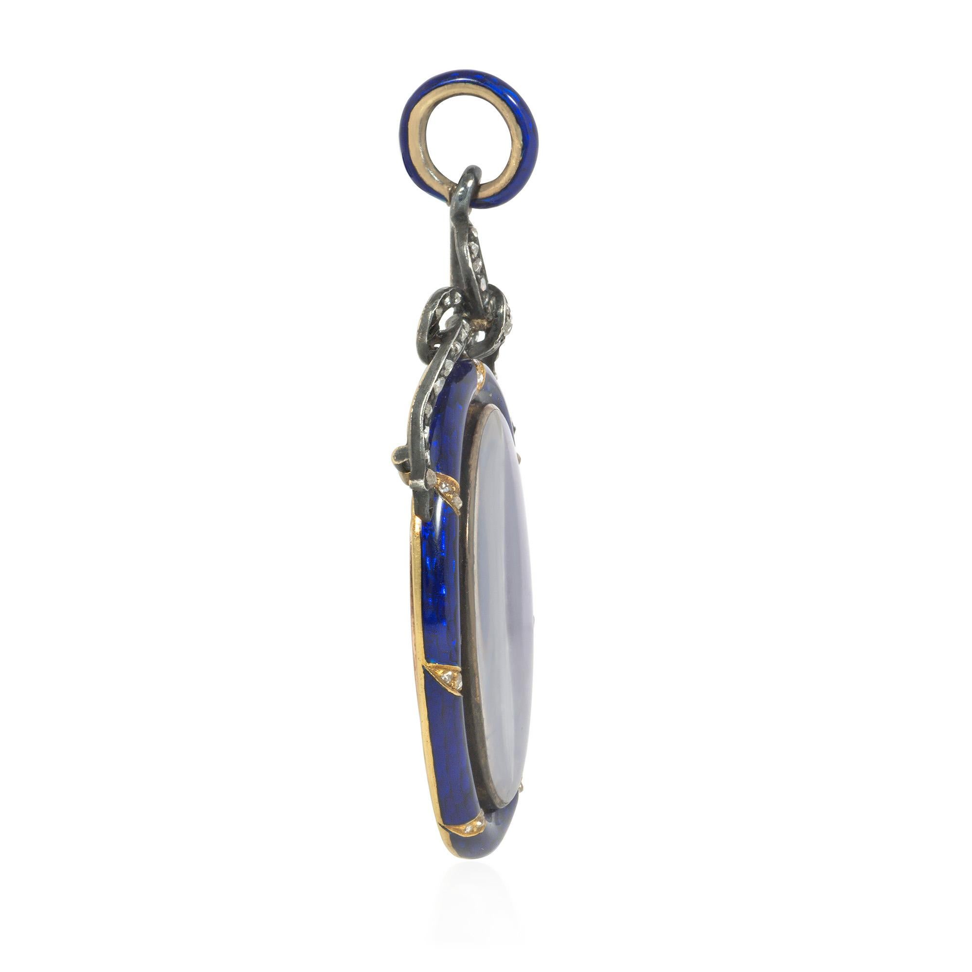 An antique Victorian period blue enamel, diamond, and gold locket pendant centered by an oval picture glass in a blue enamel border adorned with gold and diamond gadroons, topped by a silver bow set with rose-cut diamonds and suspended from a blue