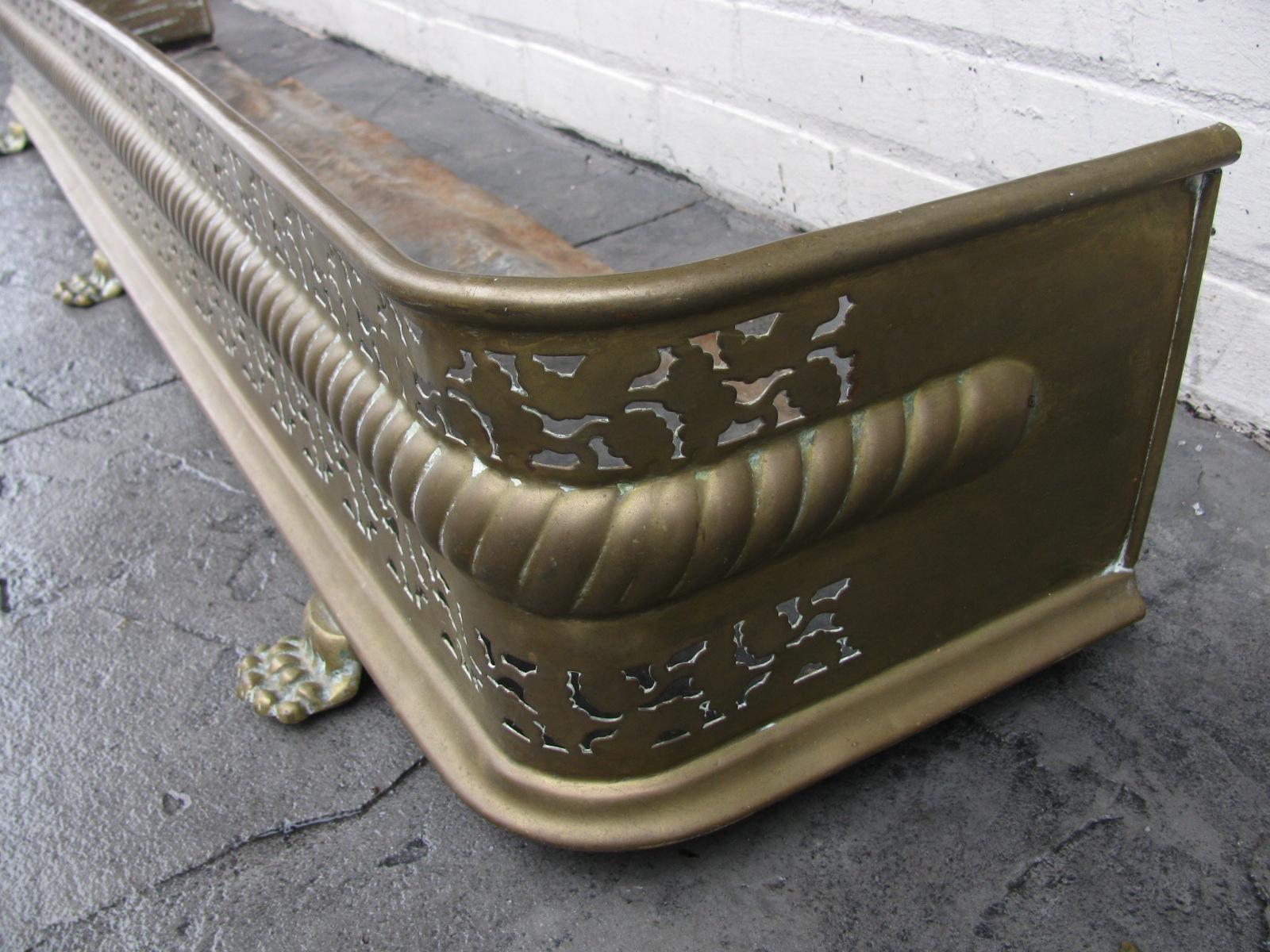 Fabulous pierced brass antique fireplace fender from England. Lions paw feet and exceptional piercing with rope banding. Mid-19th century with patina. Can be polished up if need be for a fee.