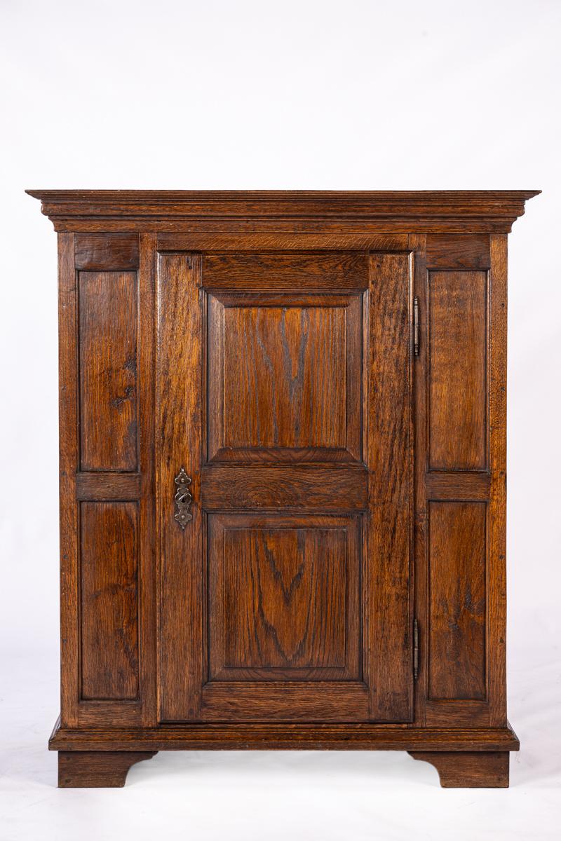 This German Westphalian oak linen cabinet is an authentic German piece of furniture with a sturdy and functional appearance, made in the mid-19th century, around 1850. The cabinet is crafted from solid oak and has a warm, deep brown color that