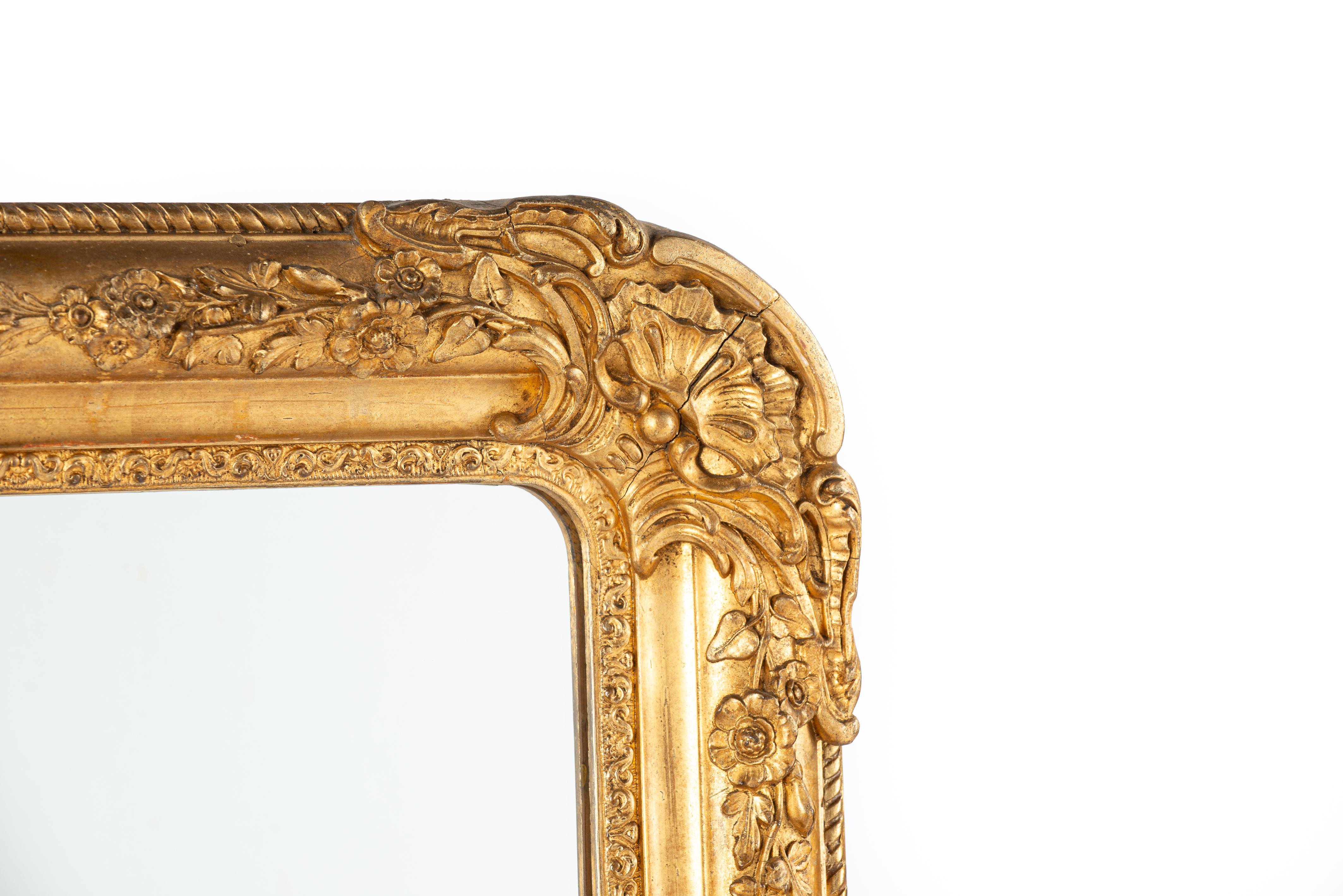 Presented here is a beautifully richly decorated antique mirror, which was made in southern France in the mid-19th century, around 1850. The mirror has rounded upper corners, characteristic of the French Louis Philippe style. At the highest point of