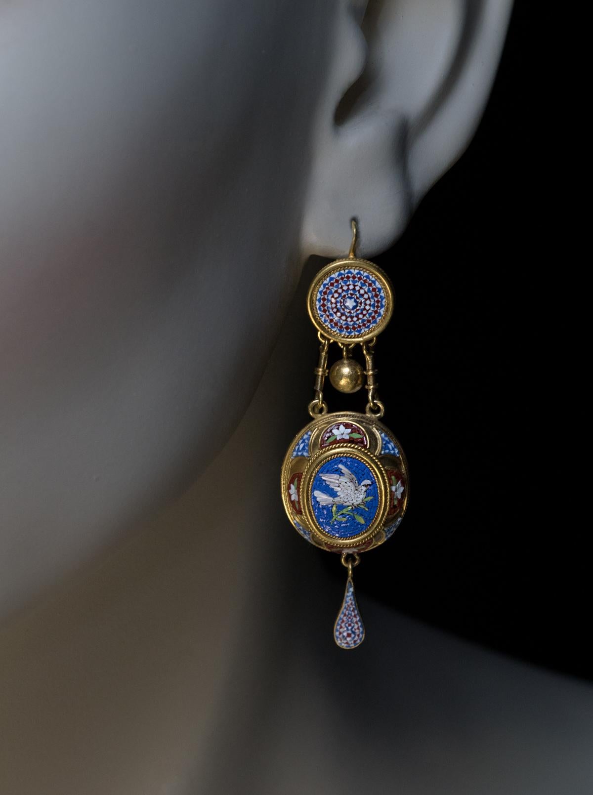 Rome, circa 1850

An early Victorian era Italian micromosaic and 18K gold set comprising dangle earrings and a brooch / pendant. The set is designed in Etruscan revival style fashionable in the mid 19th century.

The brooch / pendant features a pair