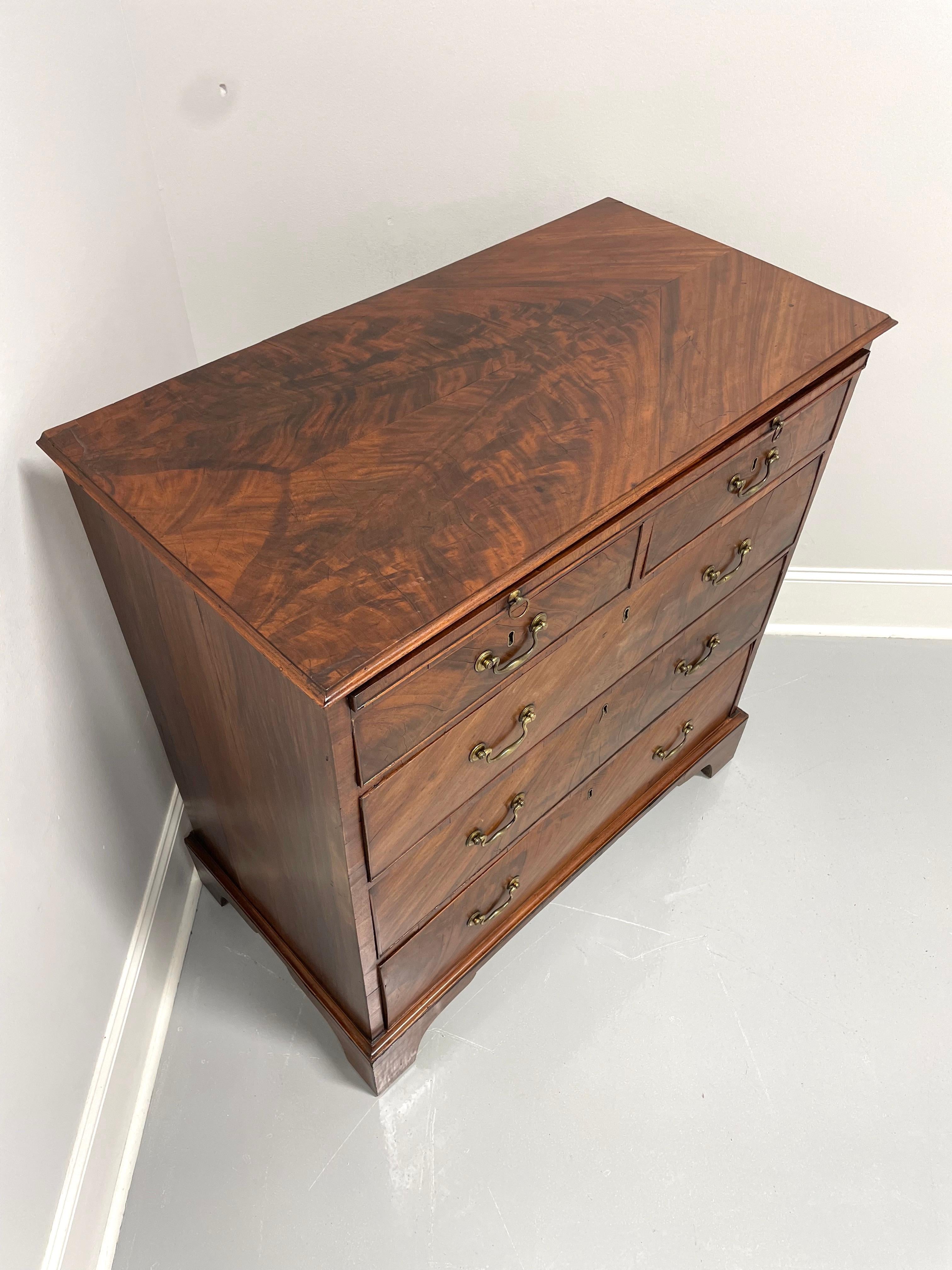 An antique Chippendale style bachelor chest, unbranded. Mahogany, flame mahogany veneers, brass hardware and bracket feet. Features brushing slide, two smaller over three larger dovetail drawers. Drawers have locks, untested, no key present. Made in