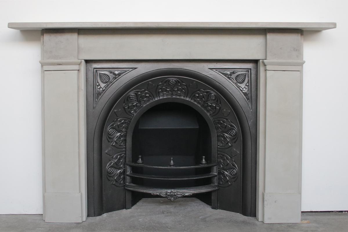 Antique restored 19th century fire surround of simple form in pale grey stone. Typical of this grey grit stone, carbon deposits can be seen throughout this fireplace

Pictured with an original cast iron arched grate, sold separately.
For detailed