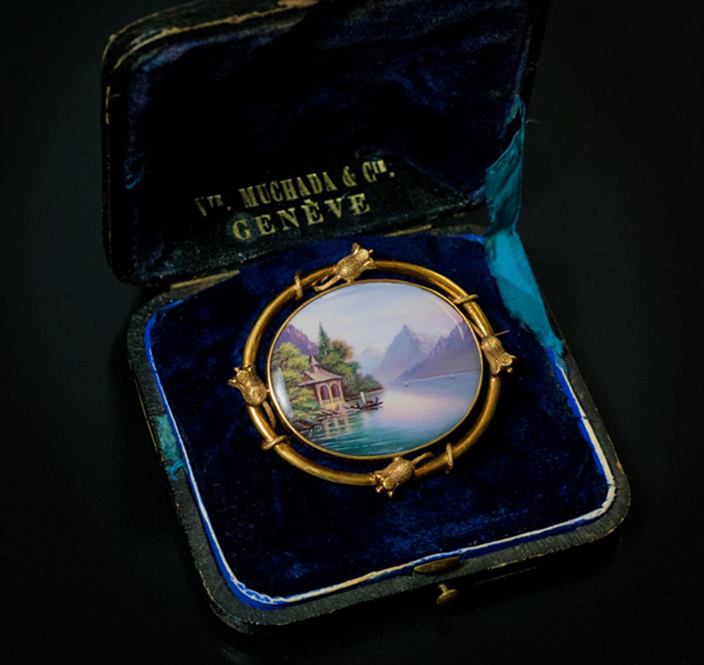 Geneva, Switzerland, circa 1850

An antique Swiss 18K gold brooch features an oval glossy enamel plaque finely painted with a view of Lake Lucerne after the 1844 painting by Thomas Miles Richardson Lake Lucerne With William Tell’s Chapel.  The