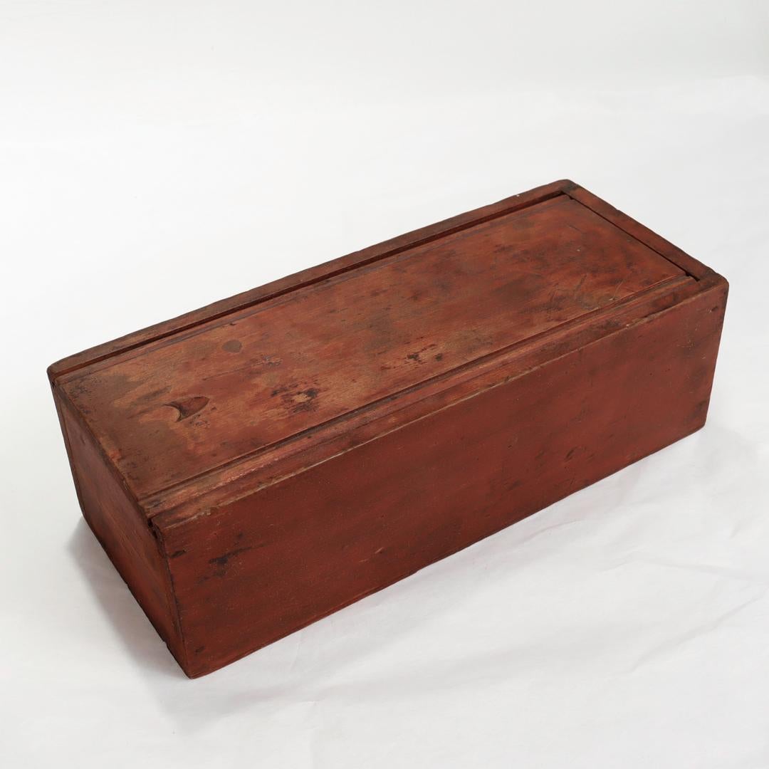 A fine antique American candle box.

In pine or fir with its original red paint. 

A rectangular candle or table box having a slide lid with carved sides & a thumb slot. 

Round nail construction.

Found in Virginia.

Simply a wonderful folky