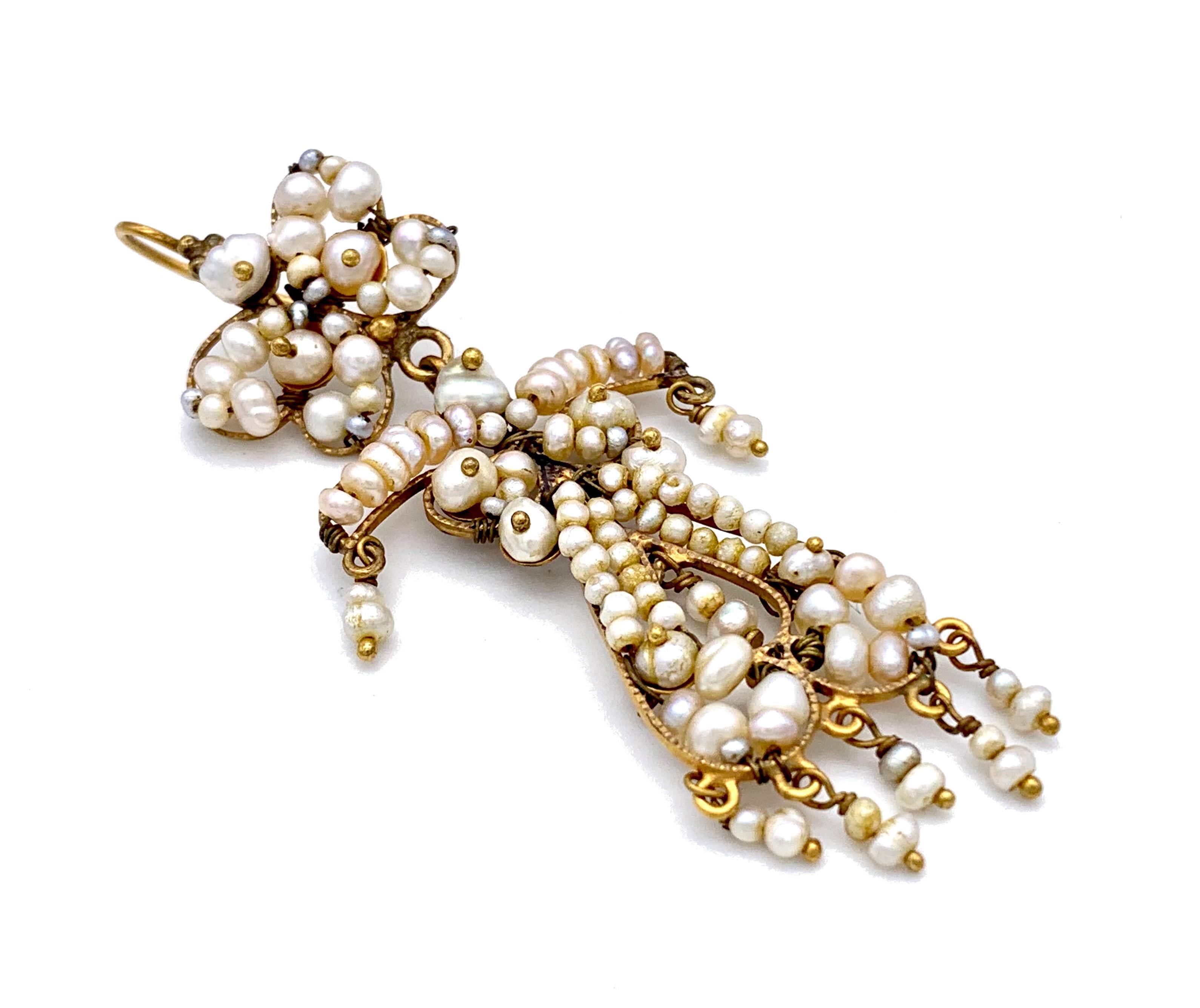 Ces élégantes boucles d'oreilles chandelier anciennes ont été fabriquées à la main en Italie au milieu du XIXe siècle. Le haut des boucles d'oreilles est conçu comme des papillons stylisés. Des perles d'eau salée naturelles de différentes tailles