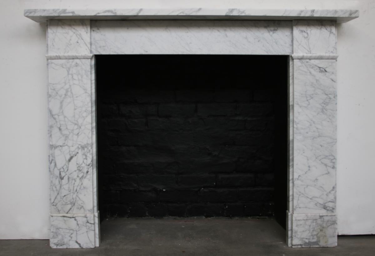 An antique Victorian fireplace surround of simple form in well figured Carrara marble. With plain jambs sit on boxed plinths and terminate in unadorned square capitals. Circa 1850.

For detailed sizes please see the size diagram in the image