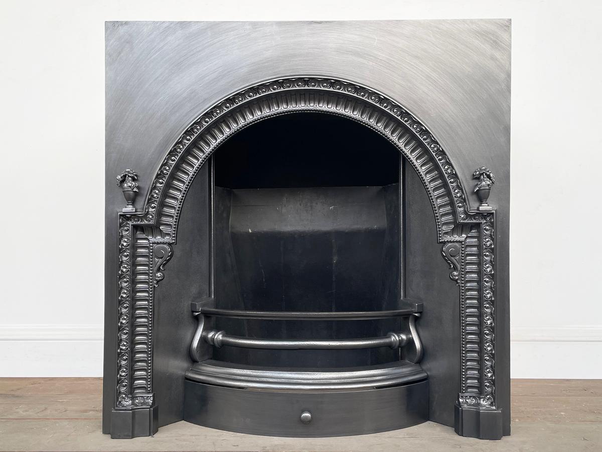 A decorative antique mid Victorian cast iron fireplace insert. The stepped arched aperture is framed by finely cast acanthus detail and fluted moulding.

This grate has been finished with traditional black grate polish to leave a gunmetal / pewter