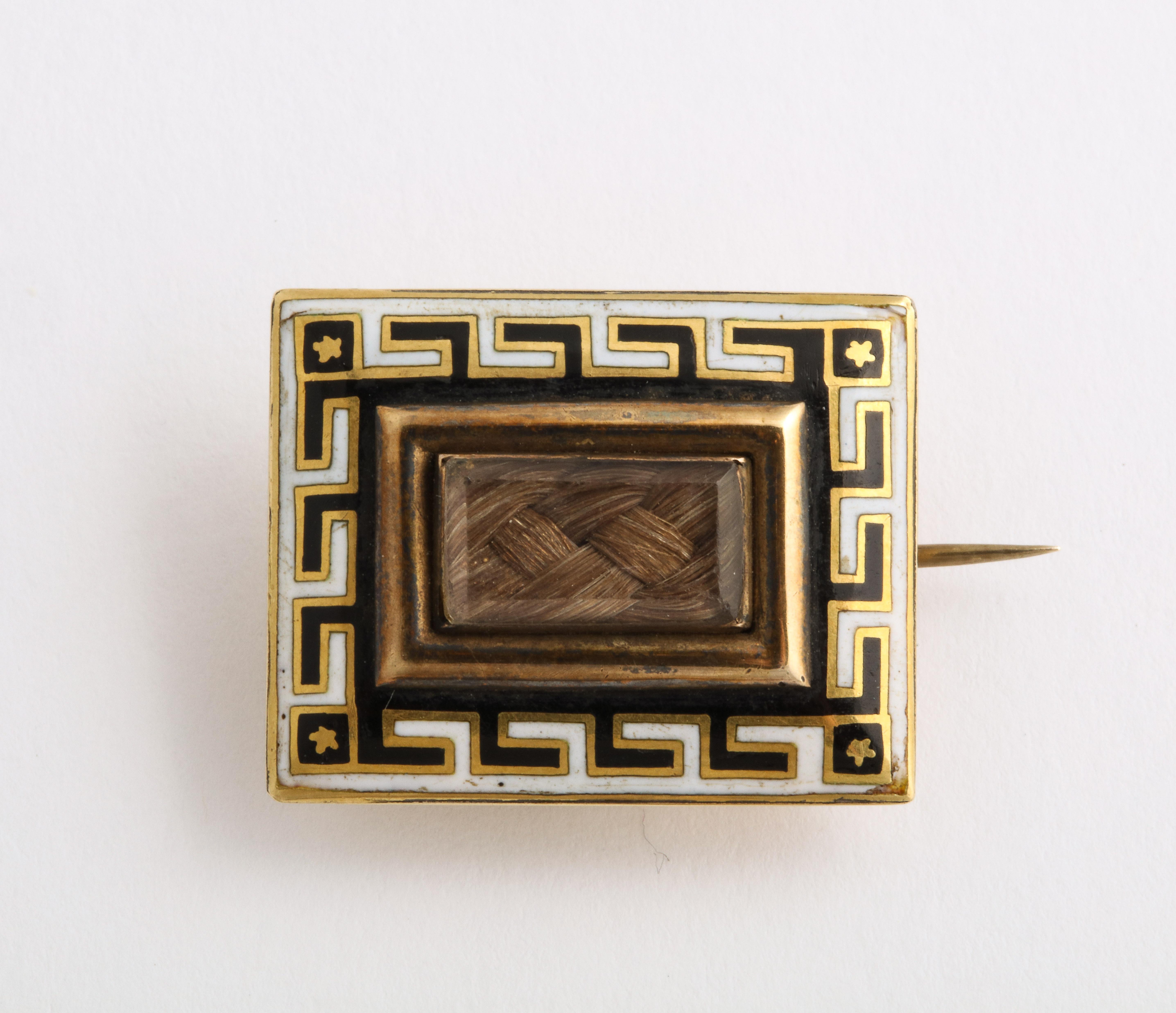 Two lovely and unique memorial brooches from the mid Victorian era executed in 15 Kt gold. The larger has an scalloped edge that is enameled with black scallops. An inner oval of black enamel frames a gold engraved border framing woven hair in