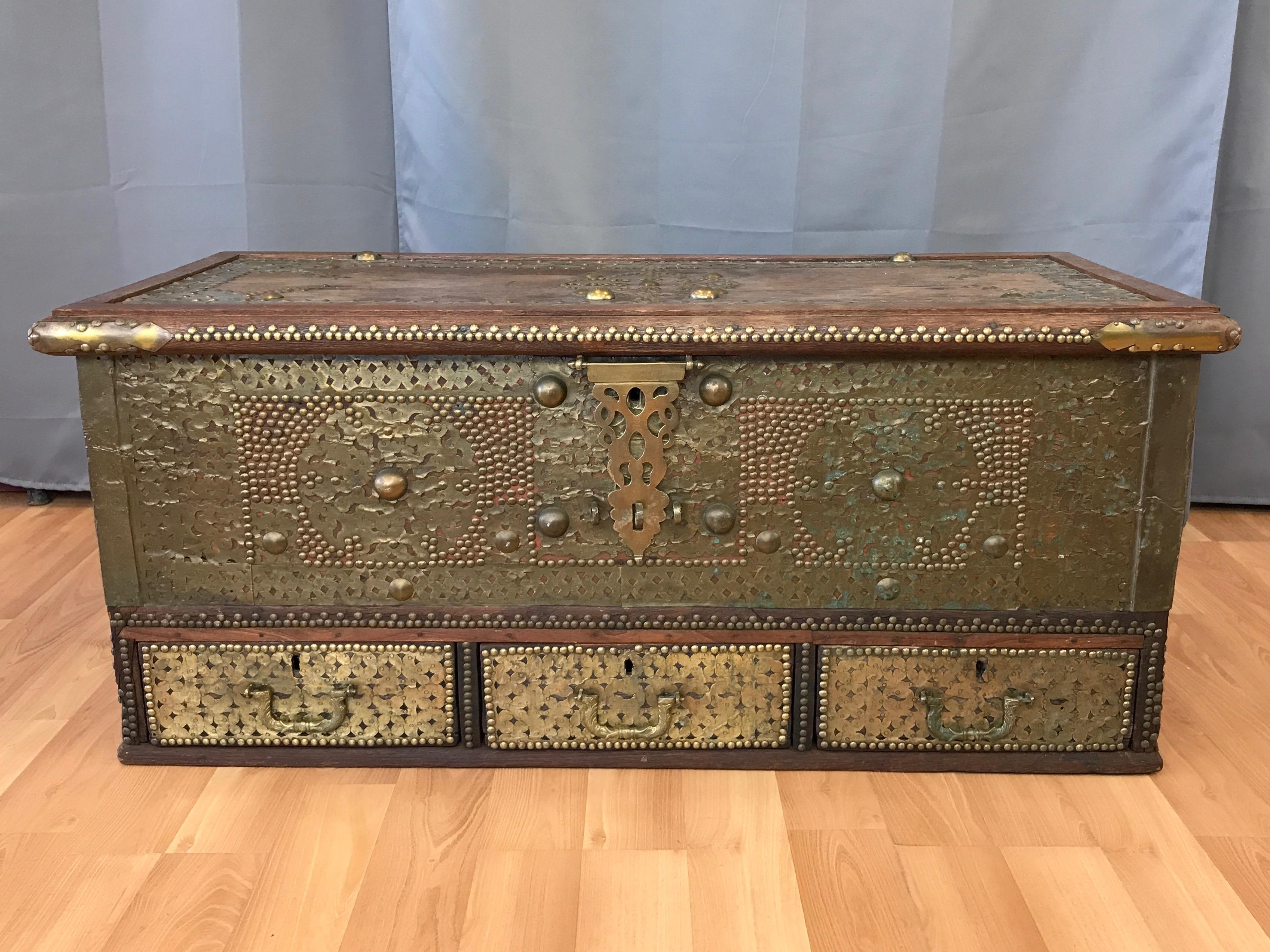 An enchanting Middle Eastern antique wood chest with drawers that features wonderfully executed brass cladding, embellishments, and hardware.

Likely of Syrian or Kuwaiti origin, this type of chest was made and used by sailors who traded along the