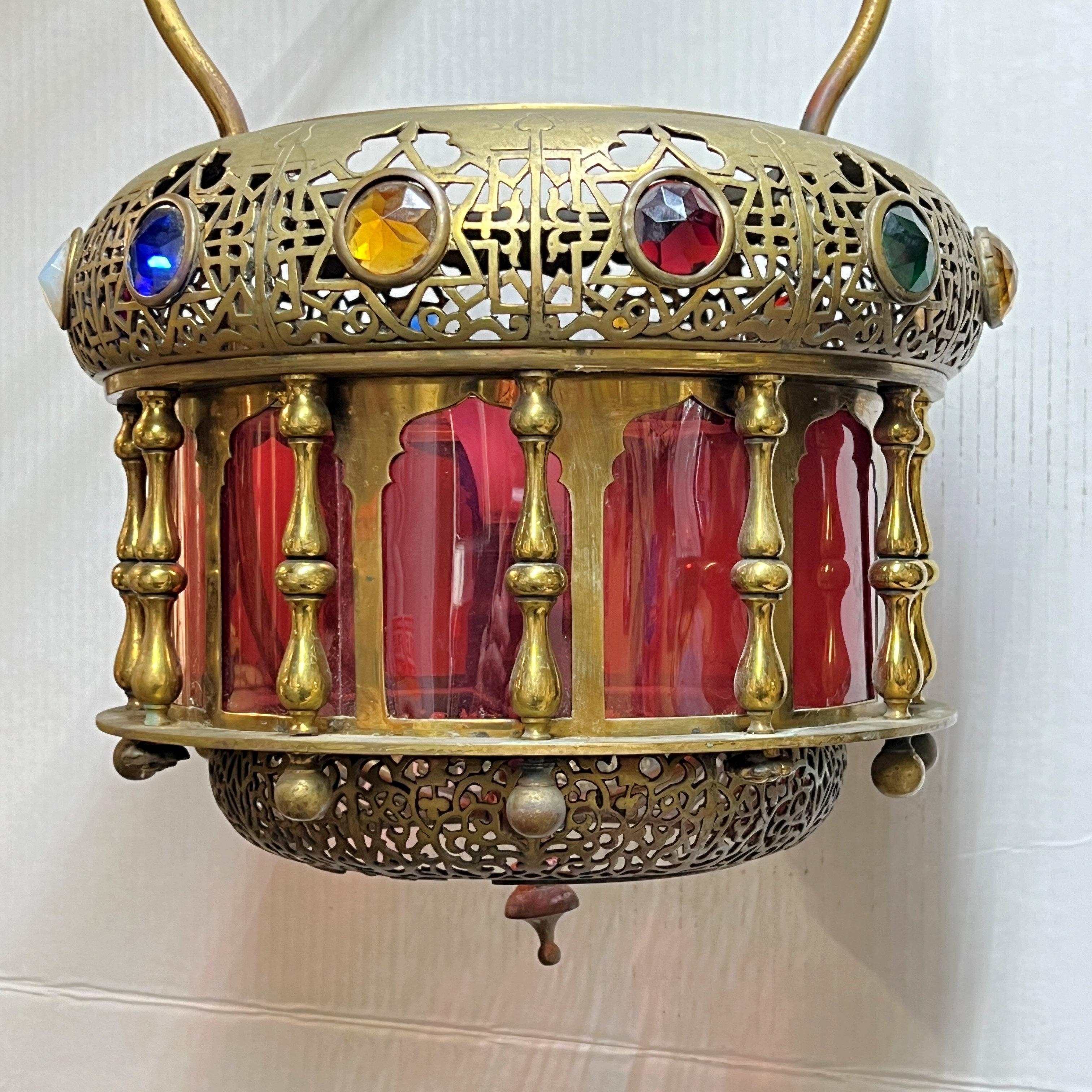 Magnifique lampe suspendue antique en bronze du Moyen-Orient datant du tout début du XXe siècle, avec une prise électrique de taille standard, des panneaux en verre rouge canneberge et des pierres de verre incrustées à facettes en blanc, violet