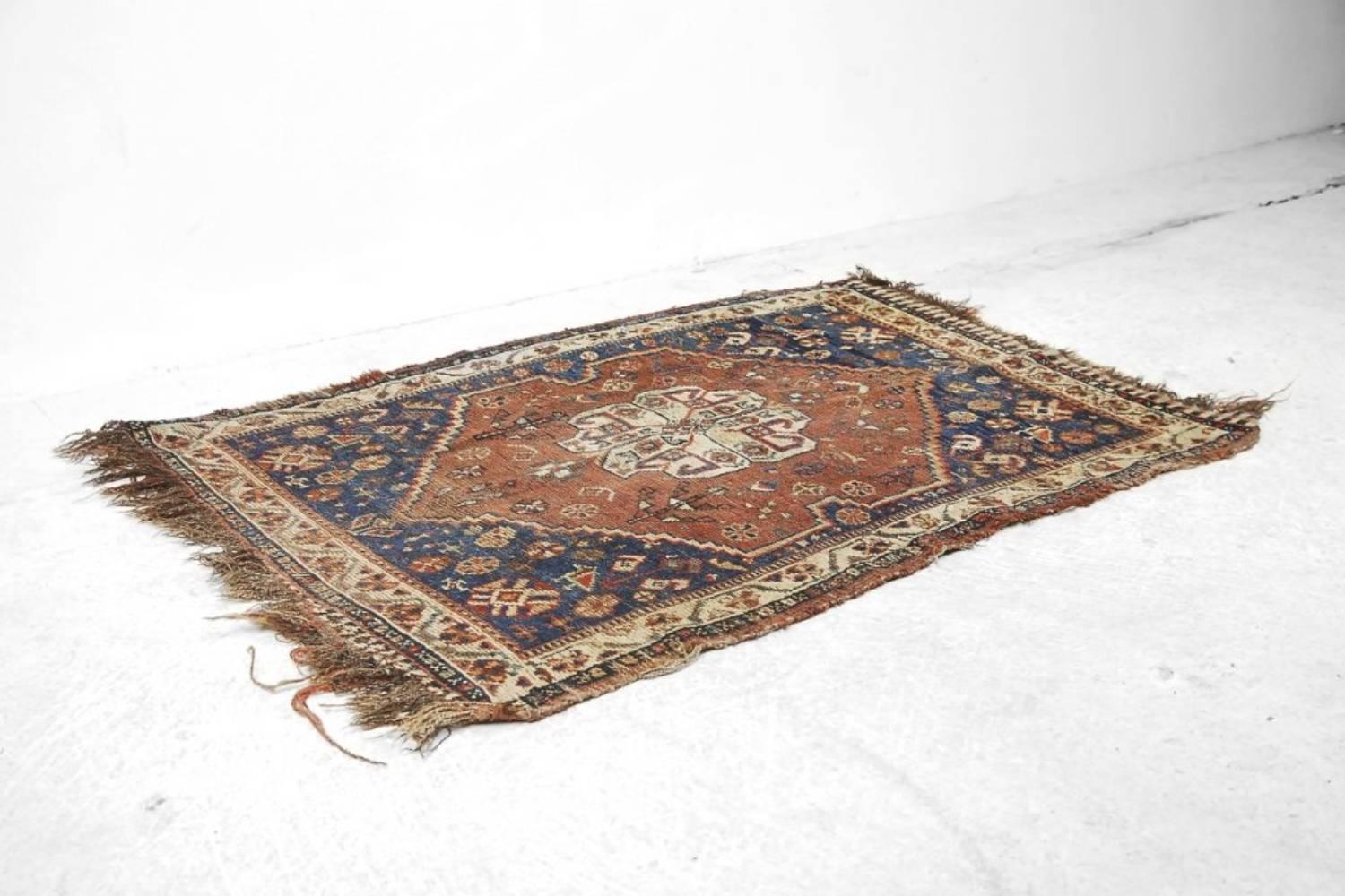 Questo antico tappeto Shiraz fatto a mano è stato prodotto nel 1880 circa in Persia (l'attuale Iran). Il tappeto presenta i tradizionali colori marrone intenso e blu scuro con motivi geometrici e tribali. Questo tappeto annodato a mano è unico, ha