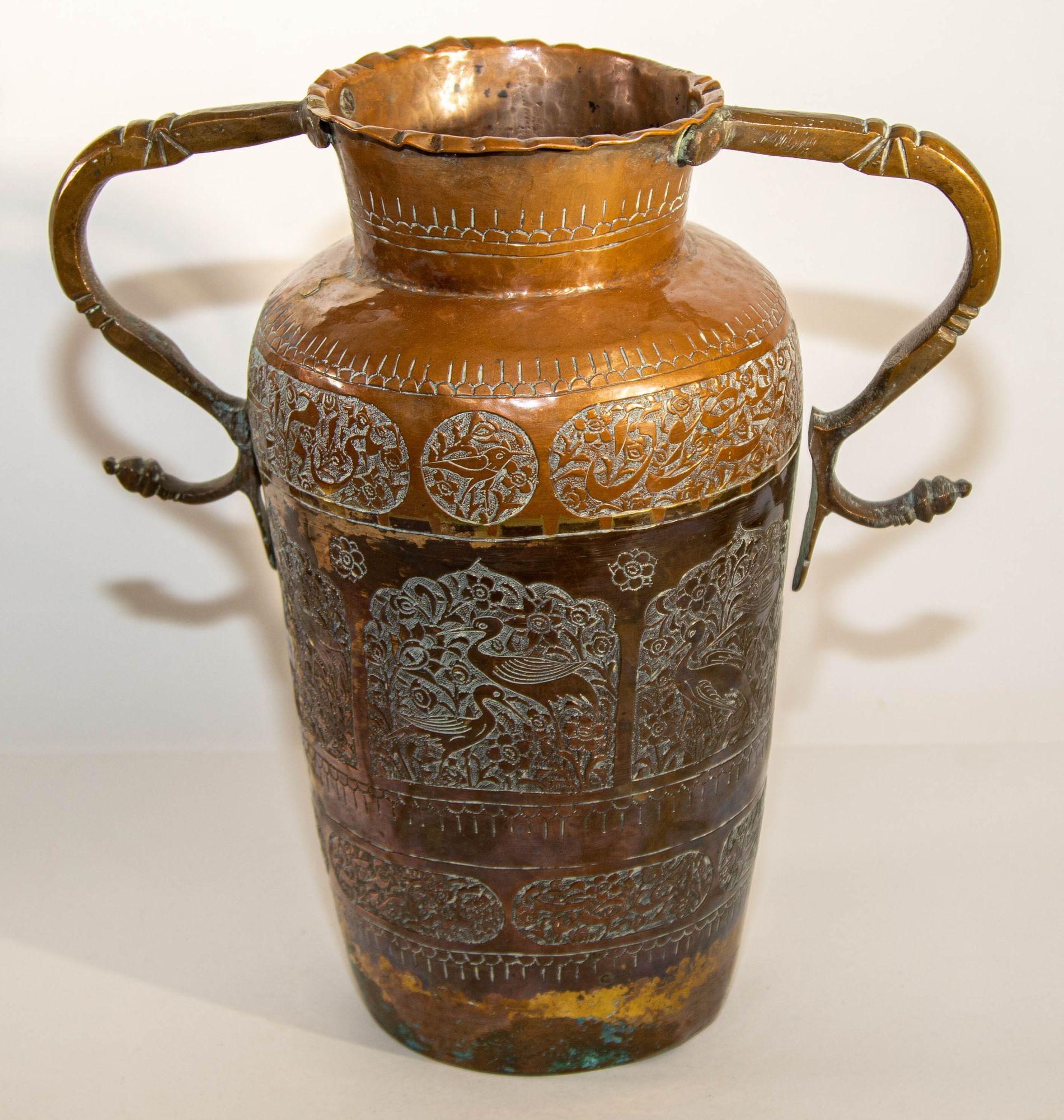 Vase en cuivre islamique du Moyen Orient du 19e siècle avec des anses en forme de serpent.
Grand vase islamique asiatique en cuivre avec un motif floral traditionnel islamique mauresque en relief et une écriture arabe, un médaillon avec des oiseaux