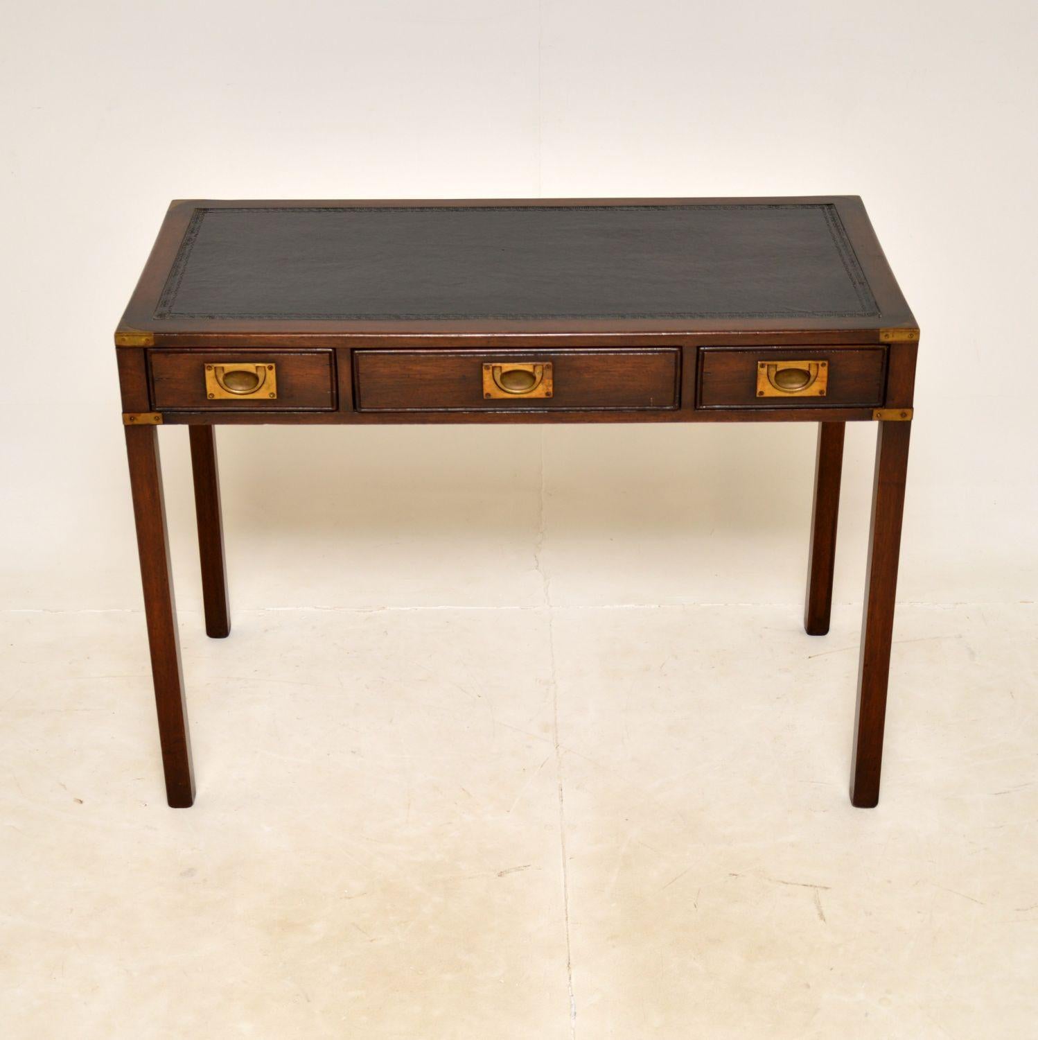 An excellent antique writing desk in the military campaign style. This was made in England, it dates from around the 1930’s.

It is very well made and has a very smart design. The dark wood is offset beautifully by the brass details. There is an