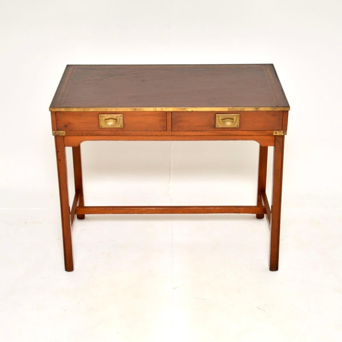 Un'elegante e ben realizzata scrivania in stile campagna militare in legno di tasso, risalente agli anni '50 circa.

È di ottima qualità, con graziose finiture in ottone e un bellissimo piano in pelle marrone. La base è allungata e anche il retro è