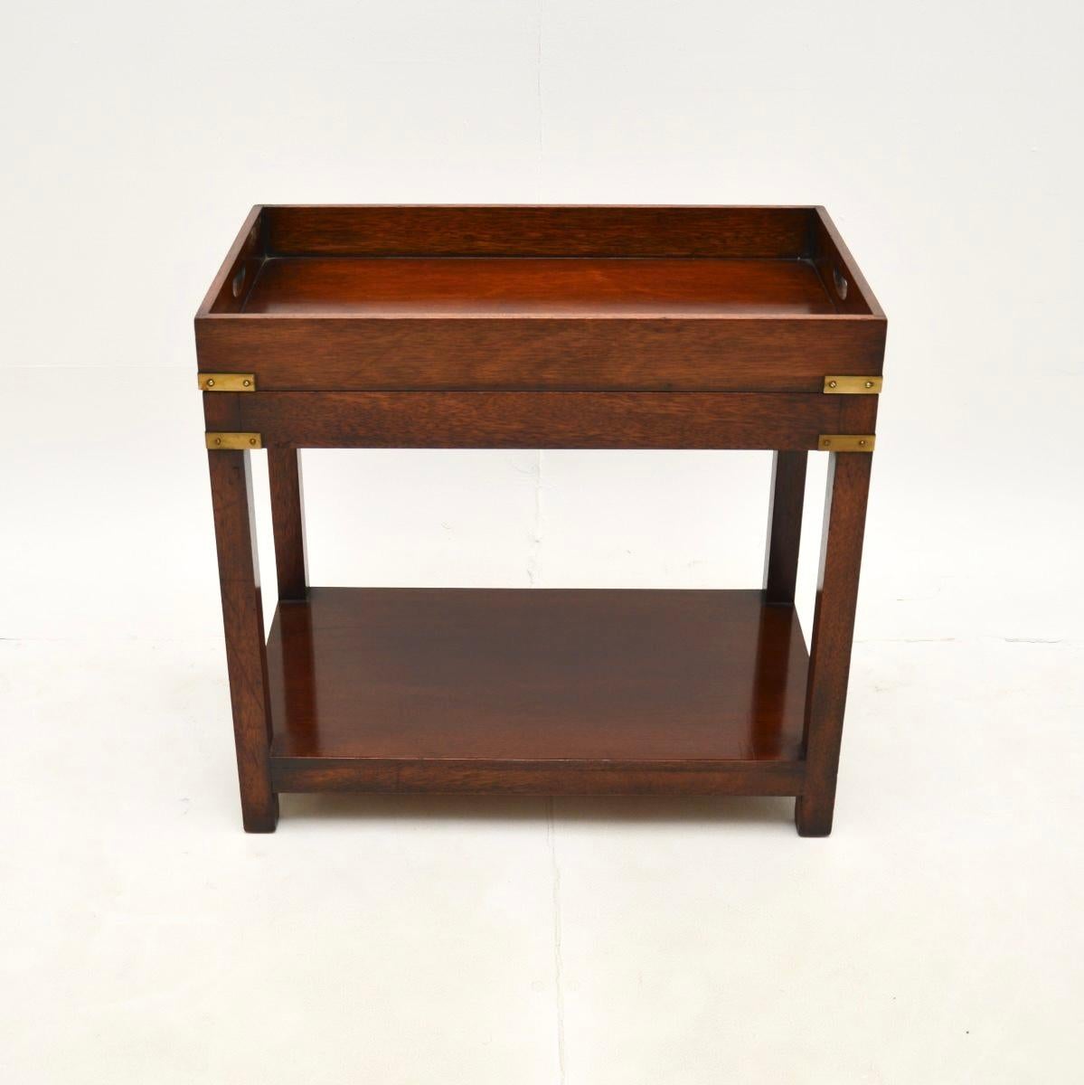 A charming and extremely well made antique military campaign style tray top side table. This was made in England and it dates from around the 1950’s.

The quality is superb, with solid construction and beautiful brass accents. The top has a raised