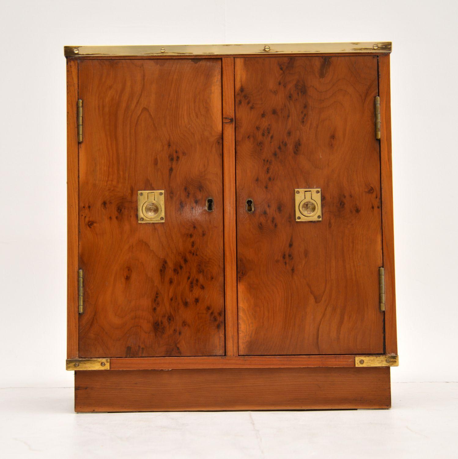 Antique military campaign style yew wood miniature cabinet dating from circa 1950s period and in excellent condition, having just been French polished. It does have a couple of brackets on the back, so it could be used as a hanging wall cabinet.