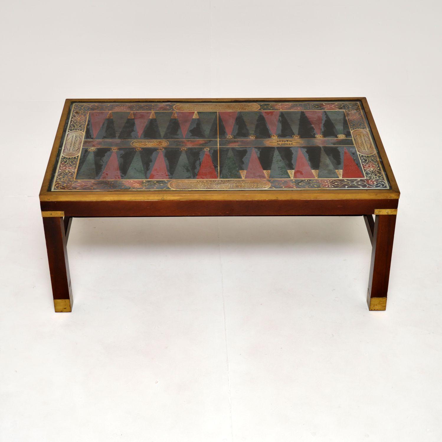 A fantastic antique military, campaign style coffee table. This was made in England, it dates from around the 1950’s.

It is of superb quality and has an unusual glass top with a large backgammon board design. It is beautifully designed and has the