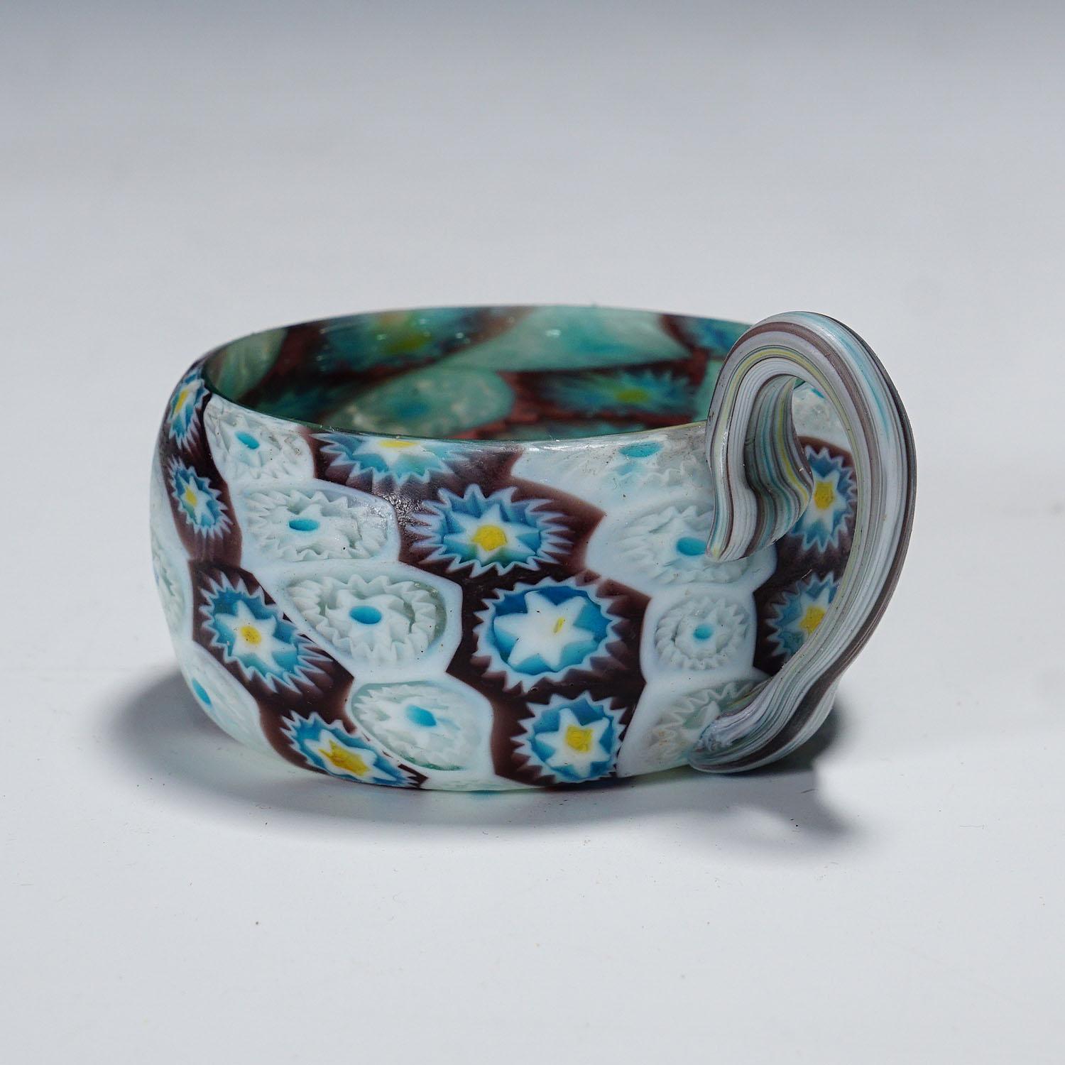 Antique Bol Millefiori avec anse, Fratelli Toso Murano ca. 1900s

Un grand bol en verre millefiori murrine avec poignée. Fabriqué par Vetreria Fratelli Toso, Murano vers 1900. Composée de murrines polychromes bleues, violettes, jaunes et blanches