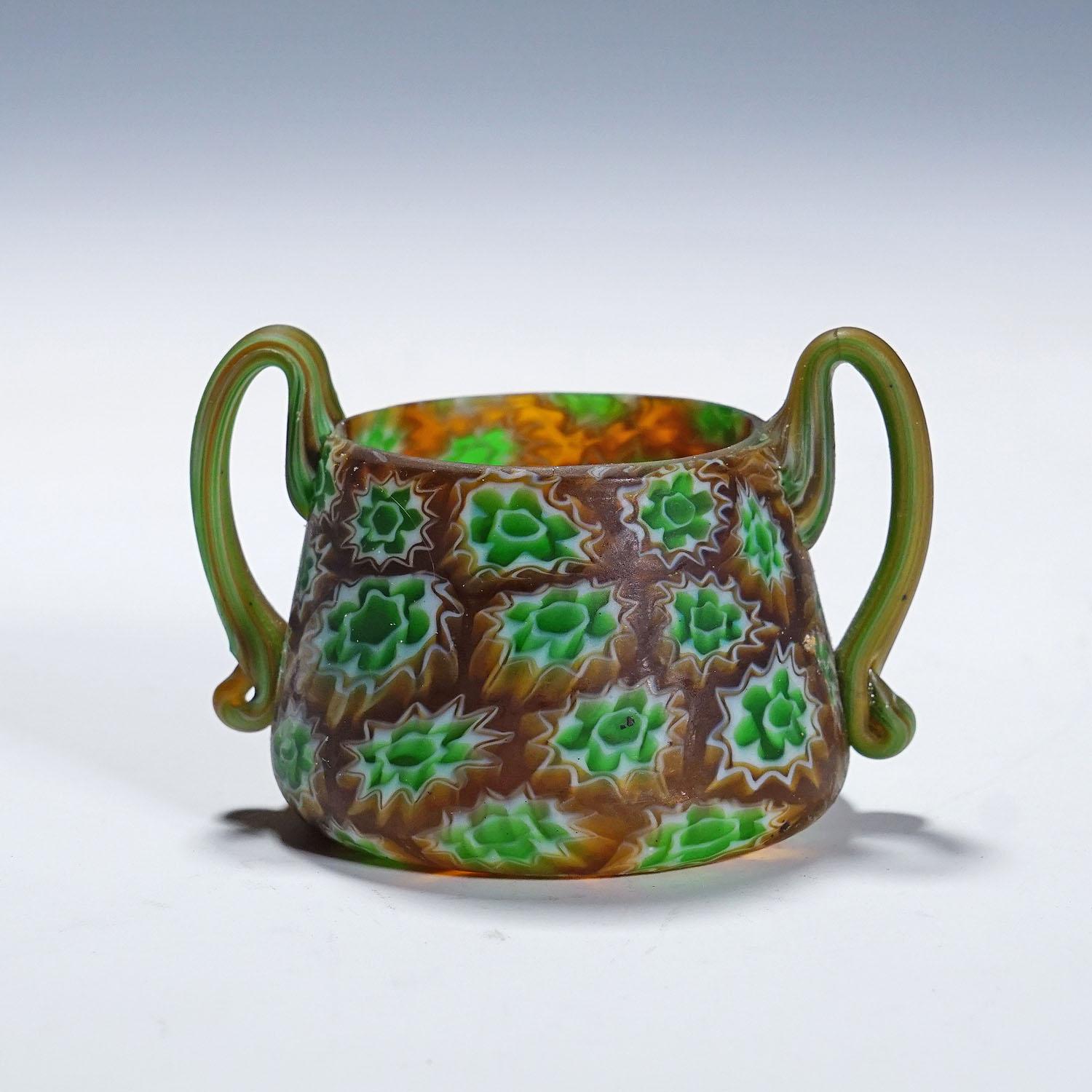 Antique Millefiori Bowl with Handles, Fratelli Toso Murano ca. 1900s

A small millefiori murrine glass bowl with two handles manufactured by Vetreria Fratelli Toso, Murano around 1900. Made of polychrome murrines in brown, green and white which were