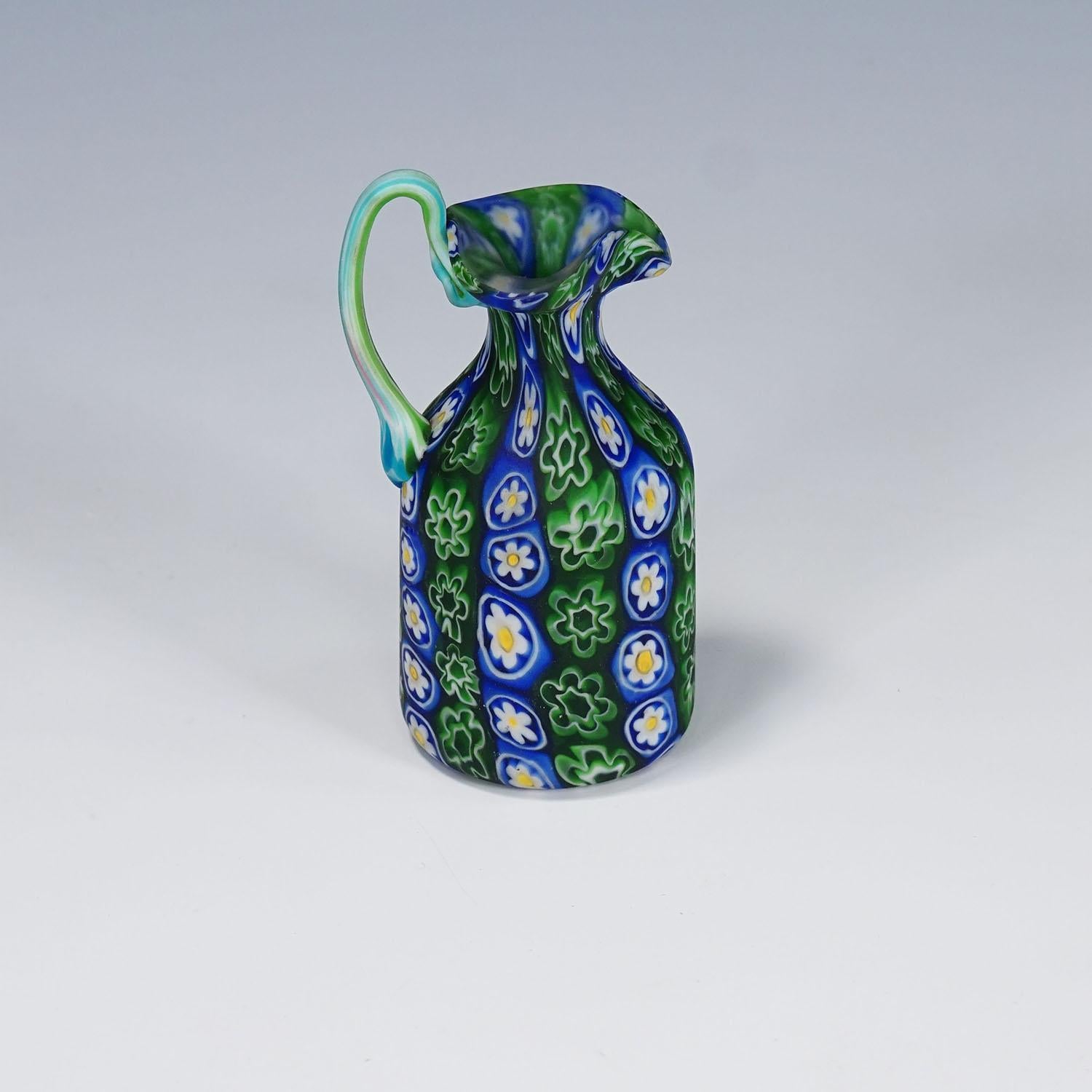 Jarra Millefiori antigua en azul y verde, Fratelli Toso Murano ca. 1920s

Una colorida jarra de cristal murrino millefiori fabricada por Vetreria Fratelli Toso, Murano, hacia 1920. Hecha de murrinas polícromas multicolores que se fundieron entre sí.