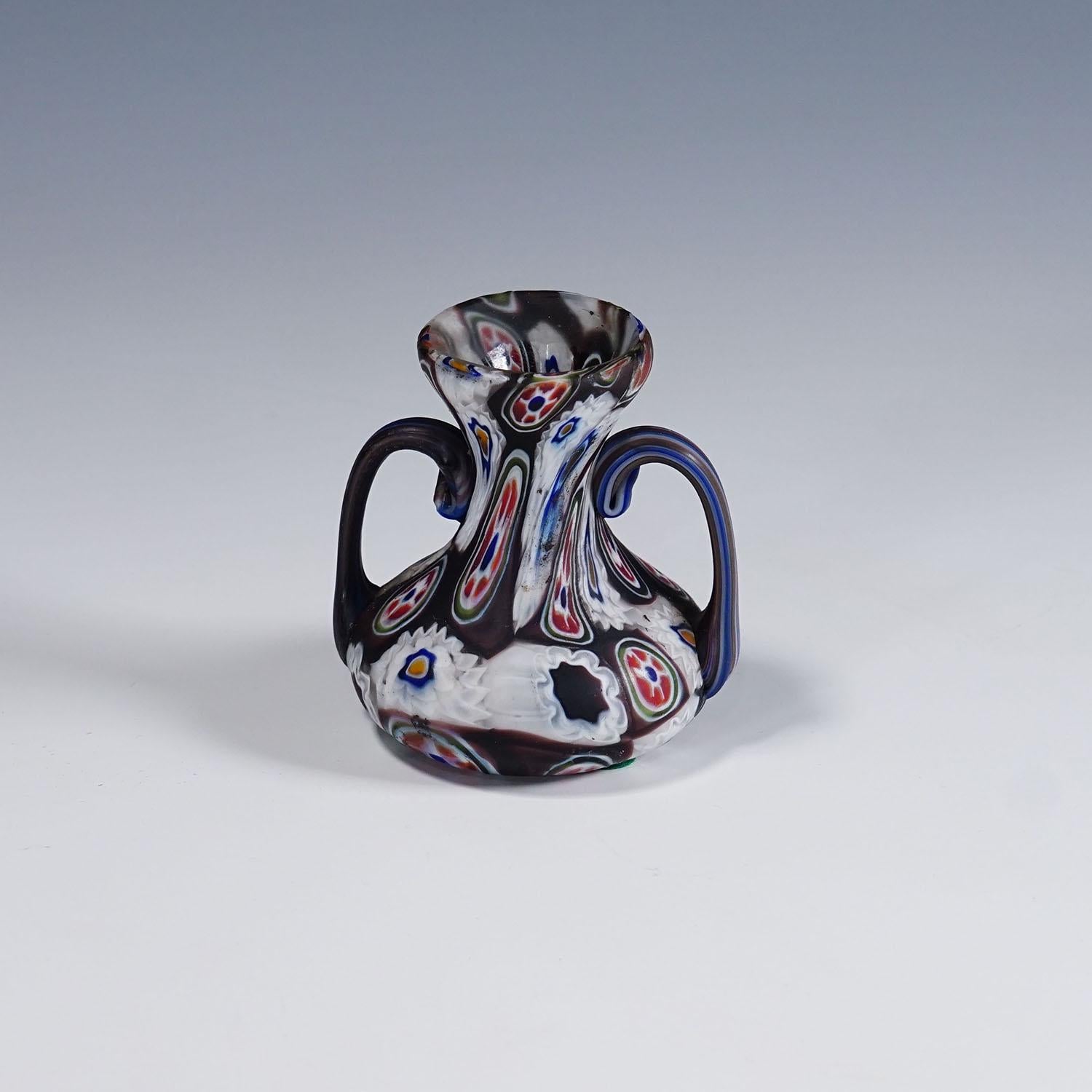 Antike Millefiori-Vase in Violett und Weiß mit Henkeln, Fratelli Toso Murano ca. 1900s

Eine farbenfrohe Millefiori-Murrine-Glasvase mit Henkeln, hergestellt von Vetreria Fratelli Toso, Murano um 1900. Hergestellt aus mehrfarbigen Murrinen, die