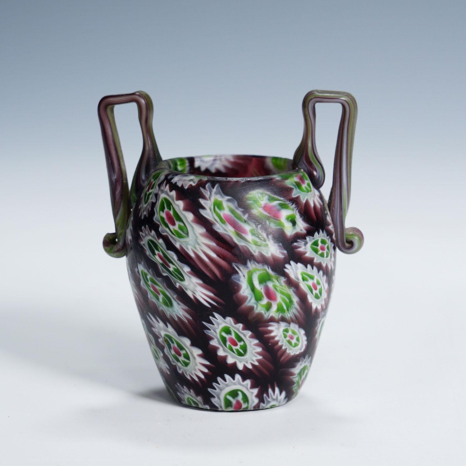 Antique Millefiori Vase with Handles, Fratelli Toso Murano ca. 1910

A small millefiori murrine glass vase in an unusual rare shape with two handles. Manufactured by Vetreria Fratelli Toso, Murano around 1910. Made of polychrome murrines (purple,