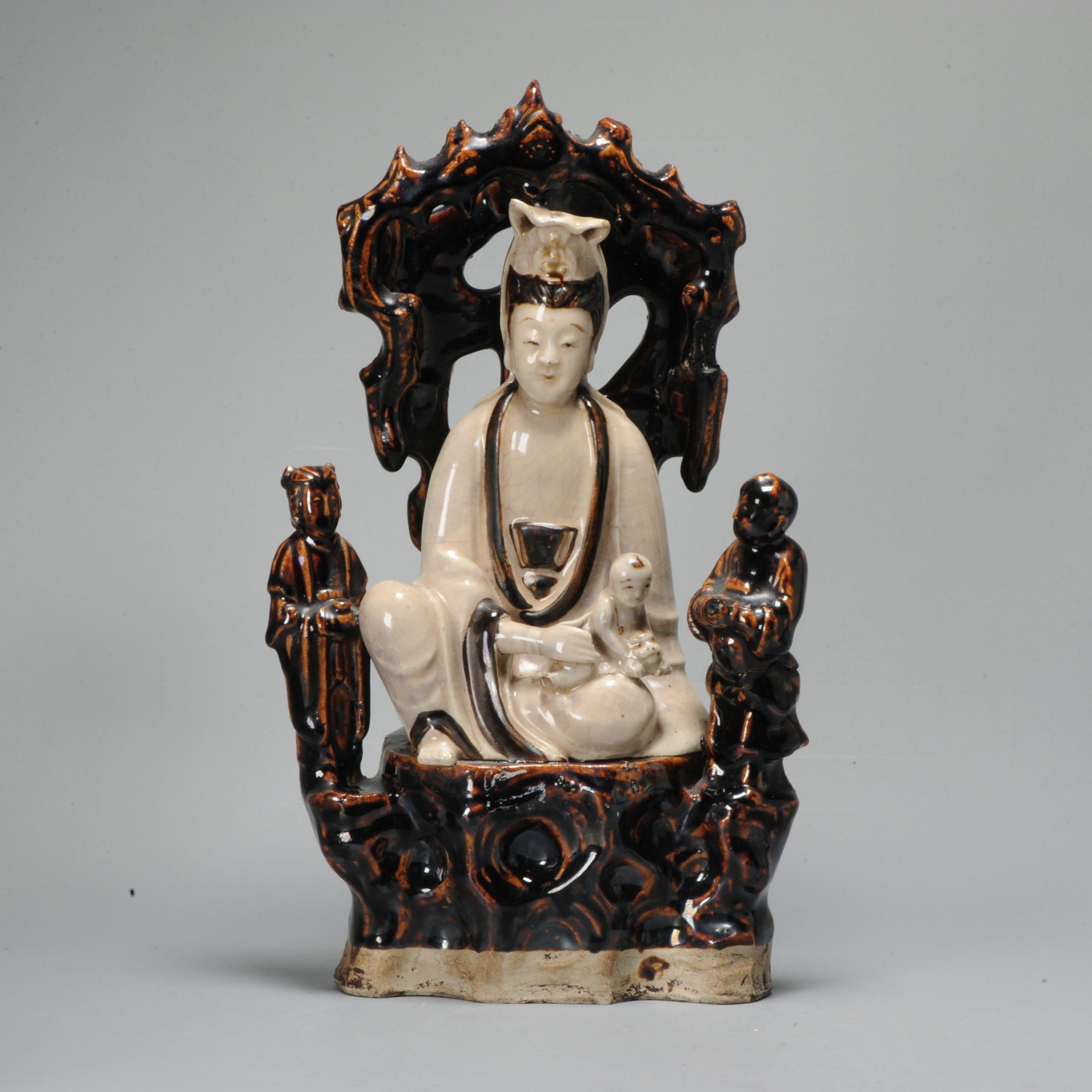 Chinese statue representing Kwan Yin/ Guanyin seated in rajalilasana on a throne, holding a child on her knees, two servants on either side. Cizhou porcelain with cream and brown glazes. Ming Dynasty (1368-1644)


Condition
The right brown