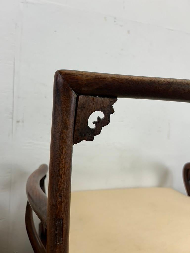Cette paire de chaises d'appoint du milieu du siècle dans le style de la dynastie Ming présente des cadres en bois massif, un magnifique grain de bois de teck, une assise basse avec un dossier sculpté orné, et des coussins amovibles avec un tissu