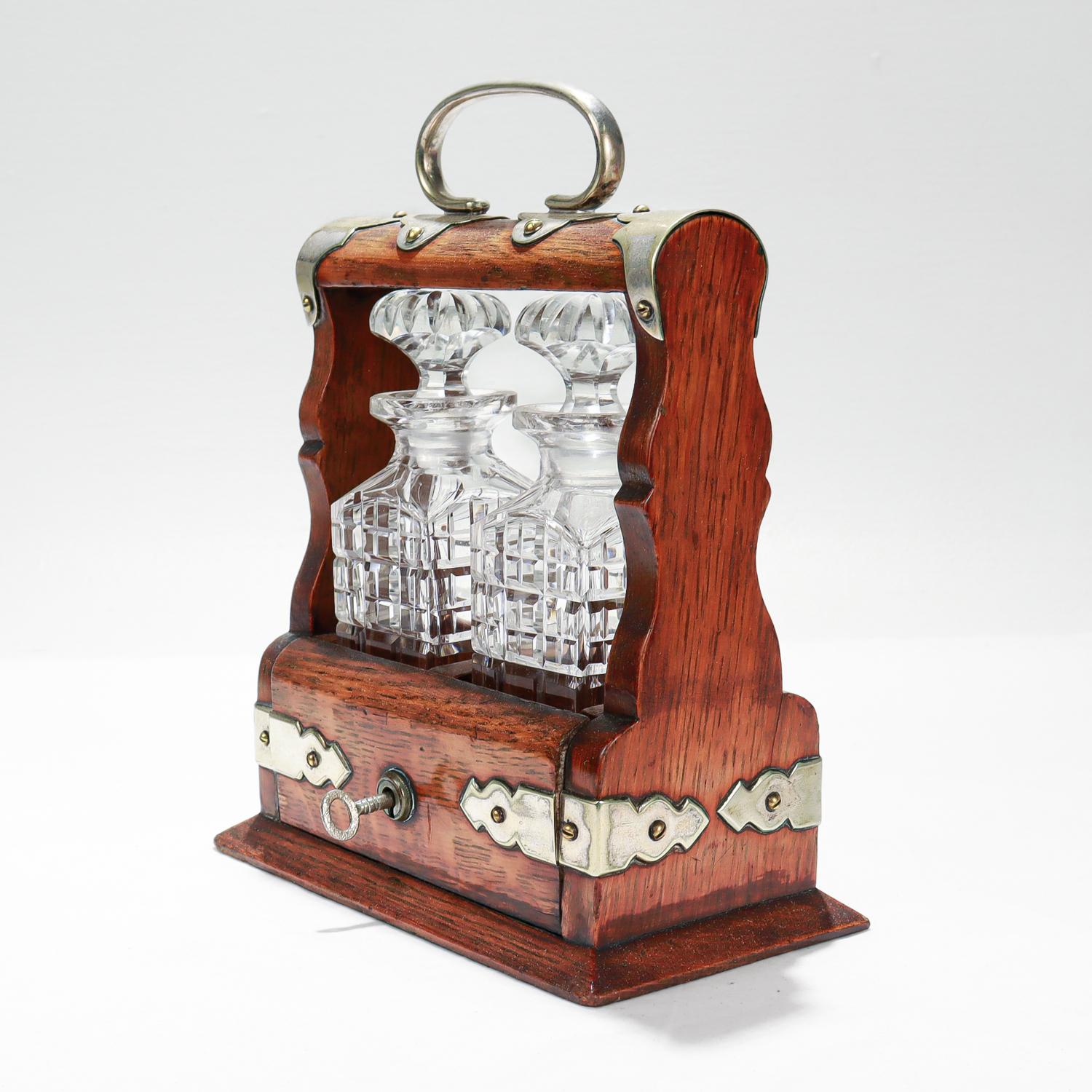 A fine antique small scale tantalus.

Meant as a travel liquor or perfume tantalus.

With square cut glass decanters or bottles in a silverplate-mounted oak frame.

Retains a functional lock and key mechanism.

Simply a wonderful small-scale