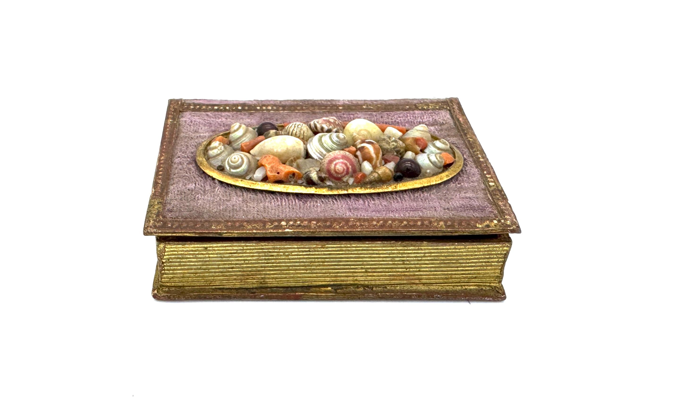 This delightful little box in the shape of a little book was created in the first half of the 19th century, around 1820-1830. It was created as a seaside souvenir. The box is covered in purple fabric that has faded on the front. The frontispiece is